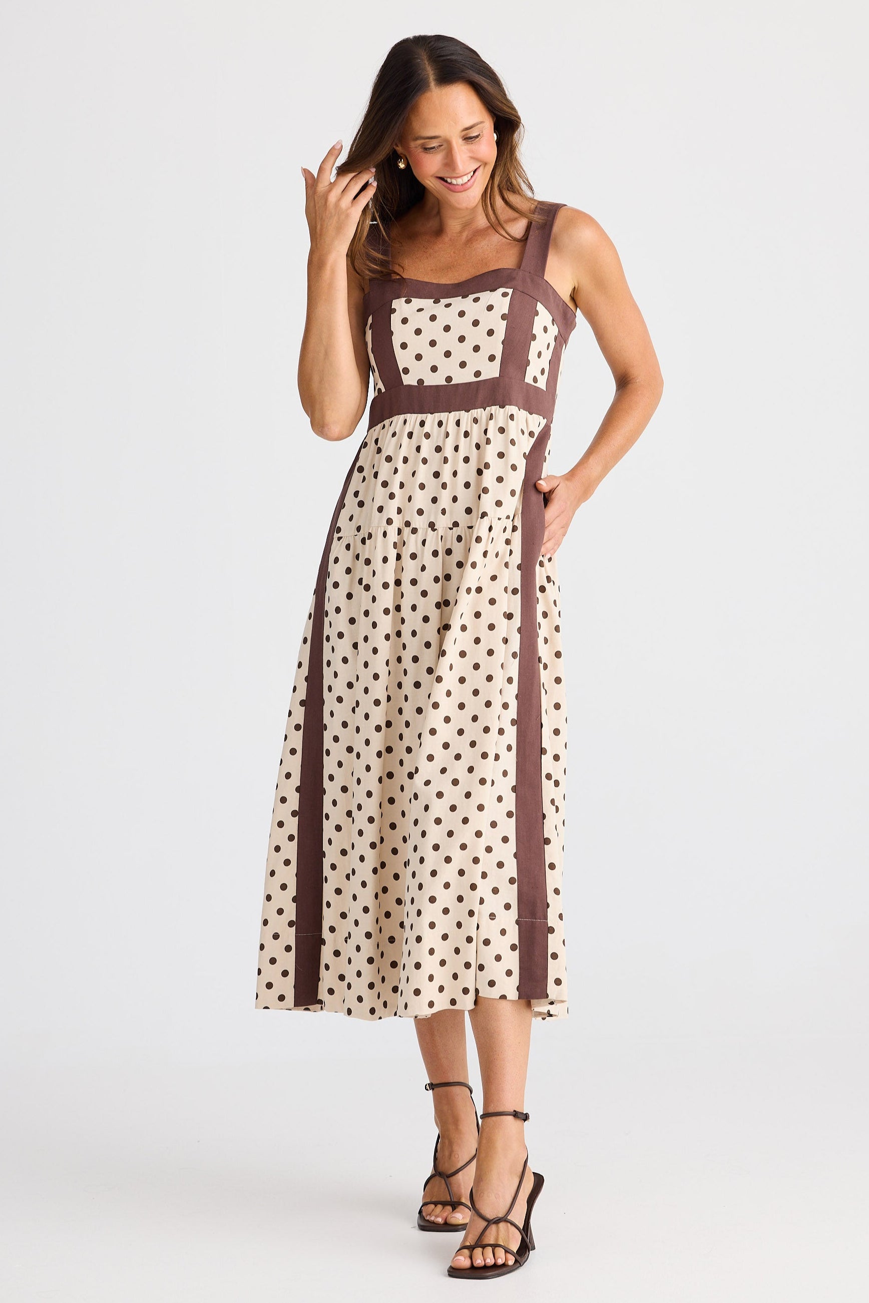 Woman wearing a polka dot dress with a brown trim on a white background