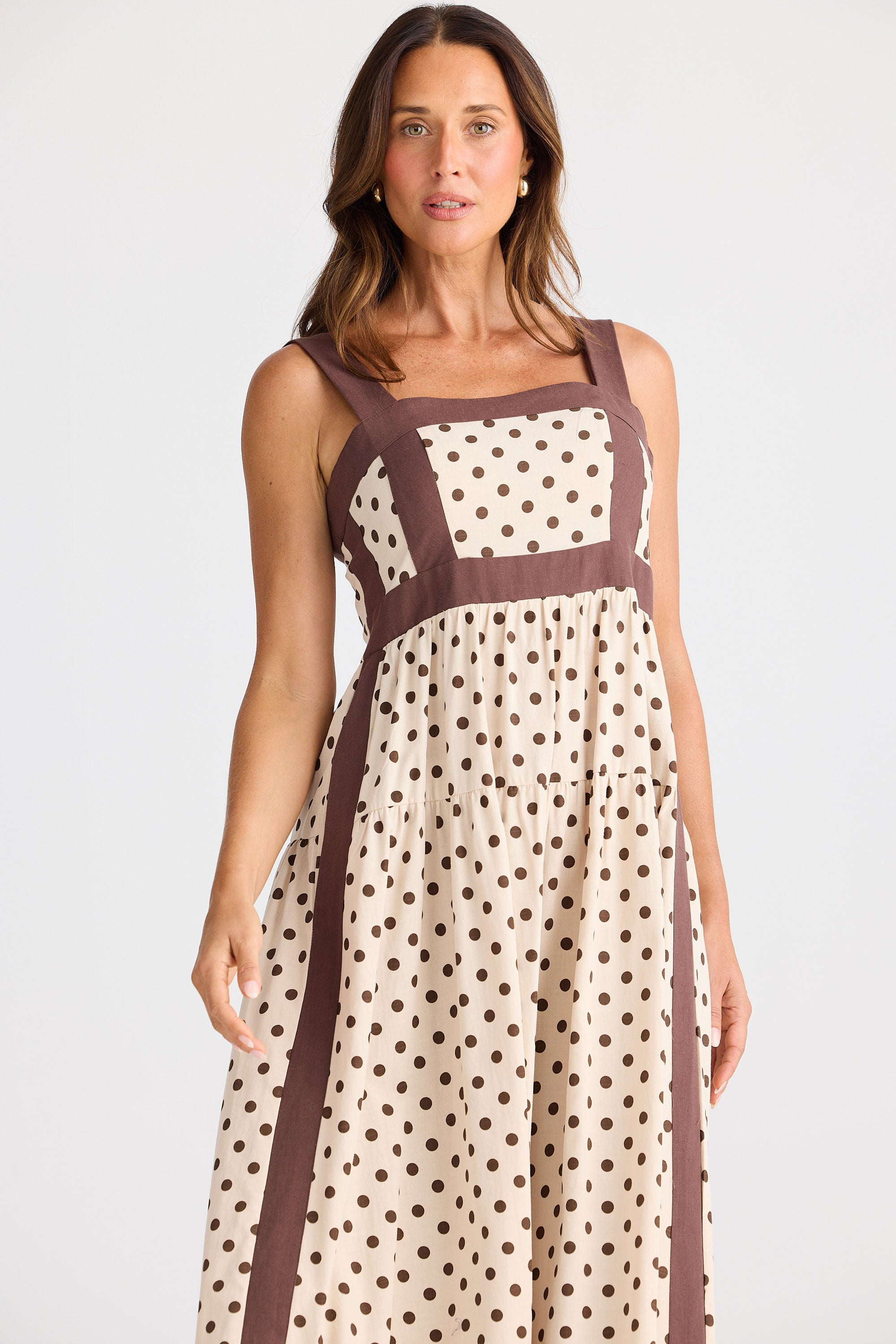 Woman wearing a polka dot dress with brown accents on a white background