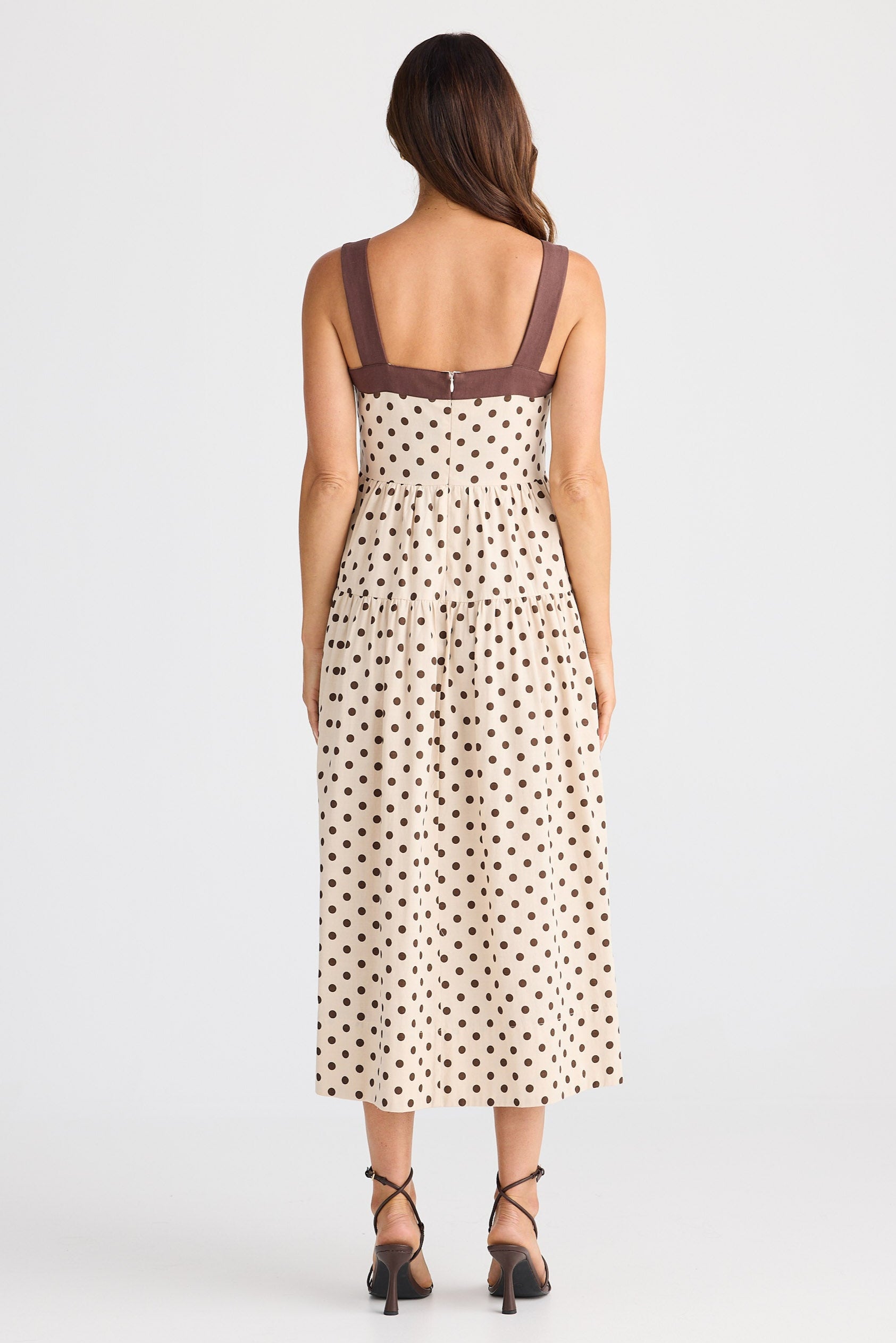 Woman wearing a polka dot dress with thin straps on a white background
