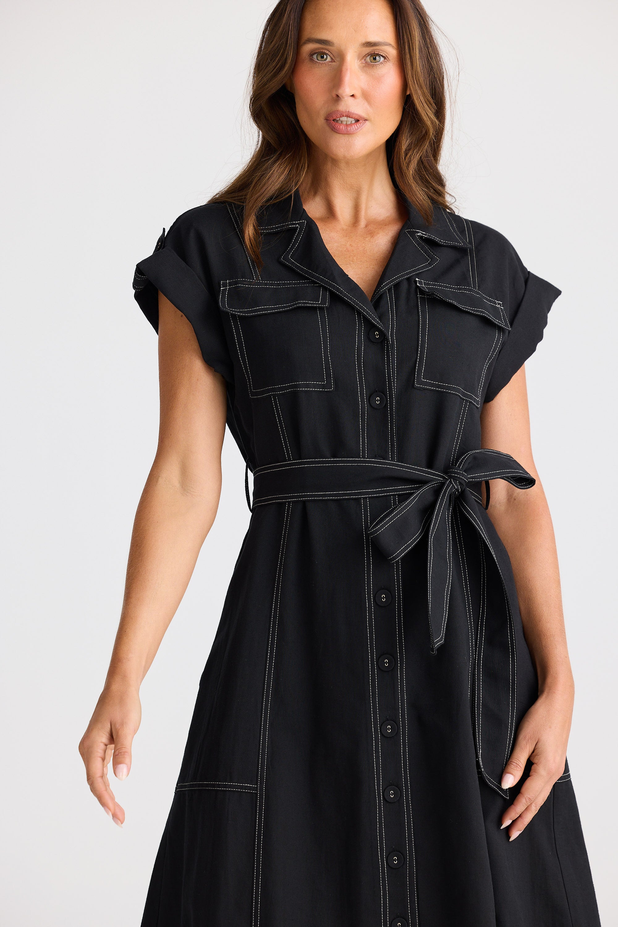 Woman wearing a black sleeveless dress with a belt on a white background