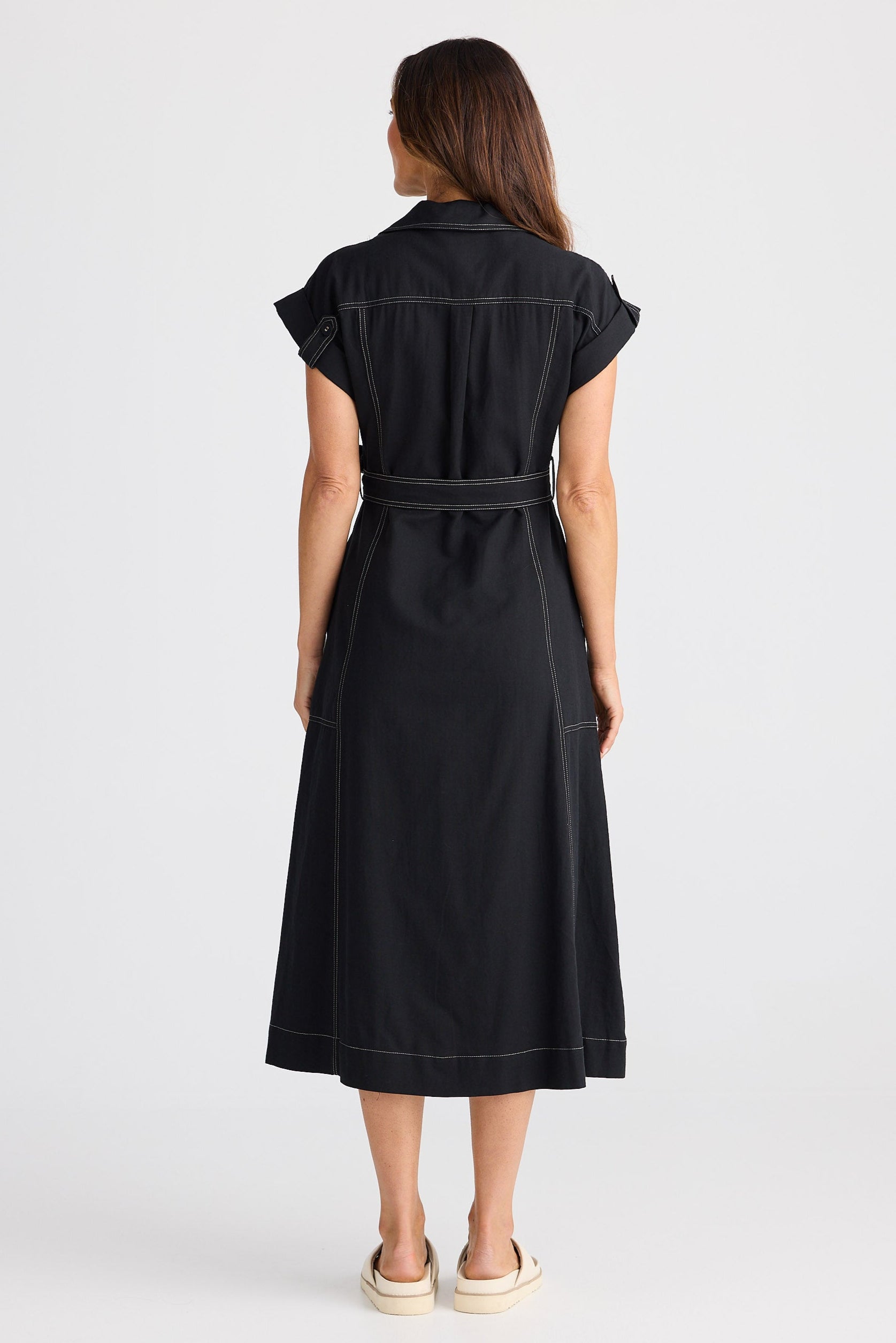Woman wearing a black dress with a belt on a white background