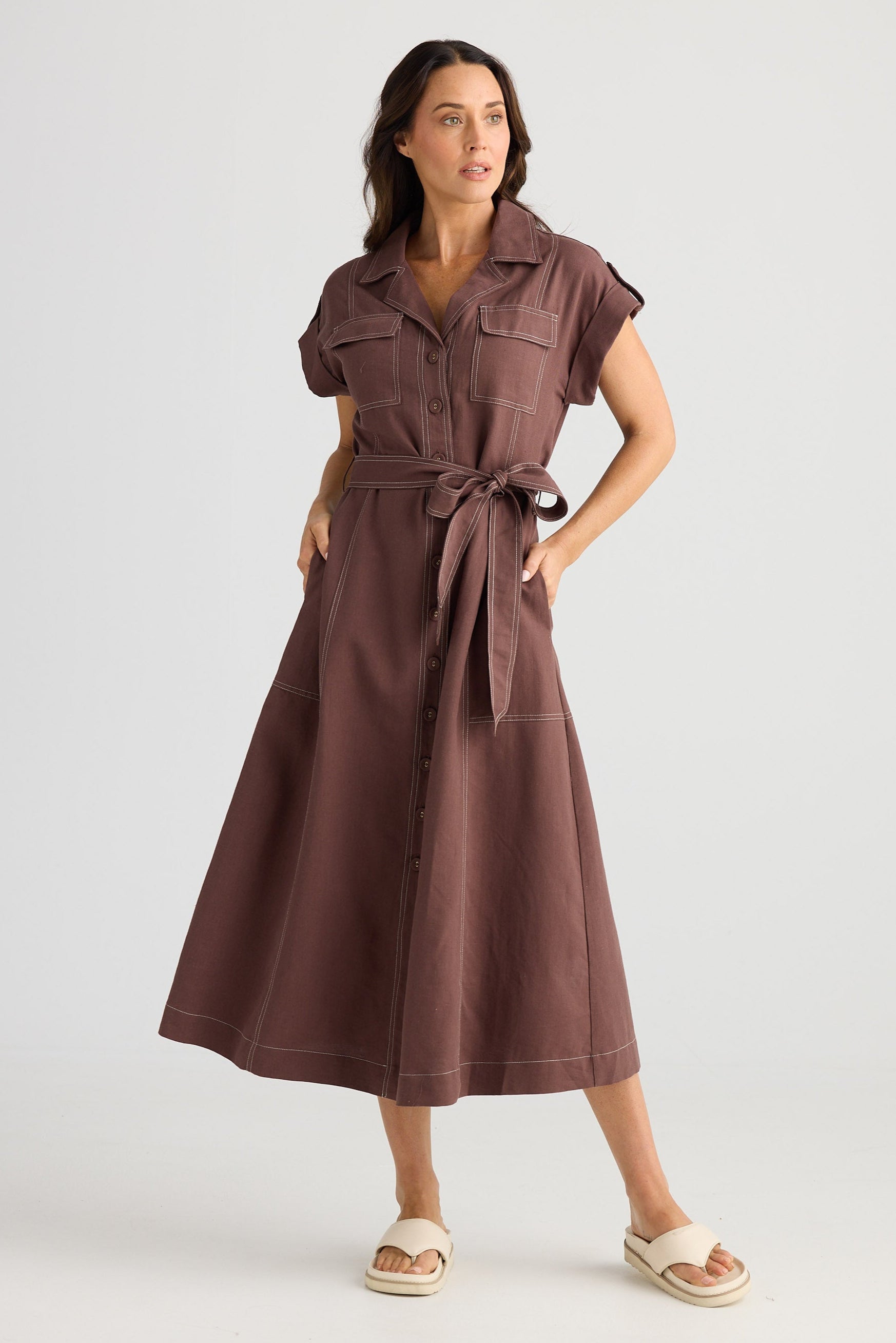 Woman wearing a brown dress with a belt on a white background