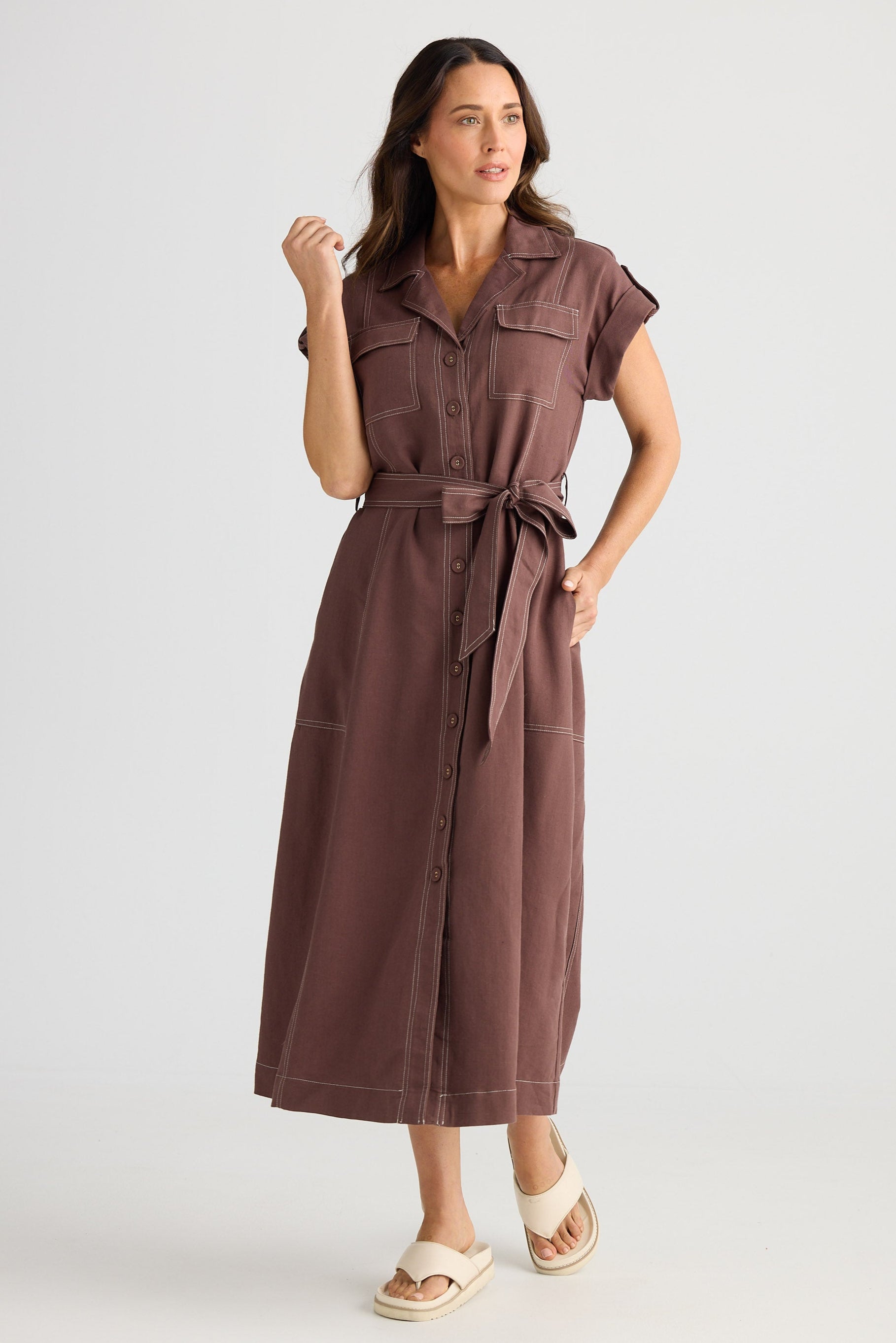 Woman wearing a brown dress with a belt on a white background