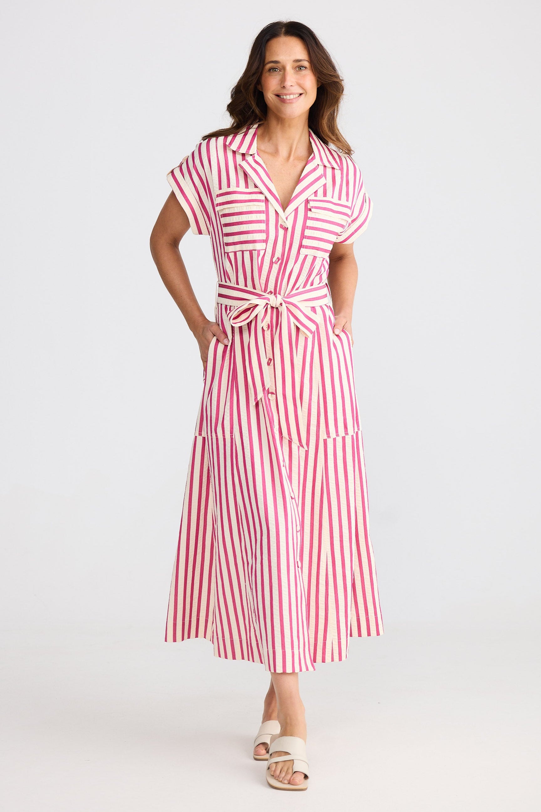 Woman wearing a hot pink and white striped dress on a white background