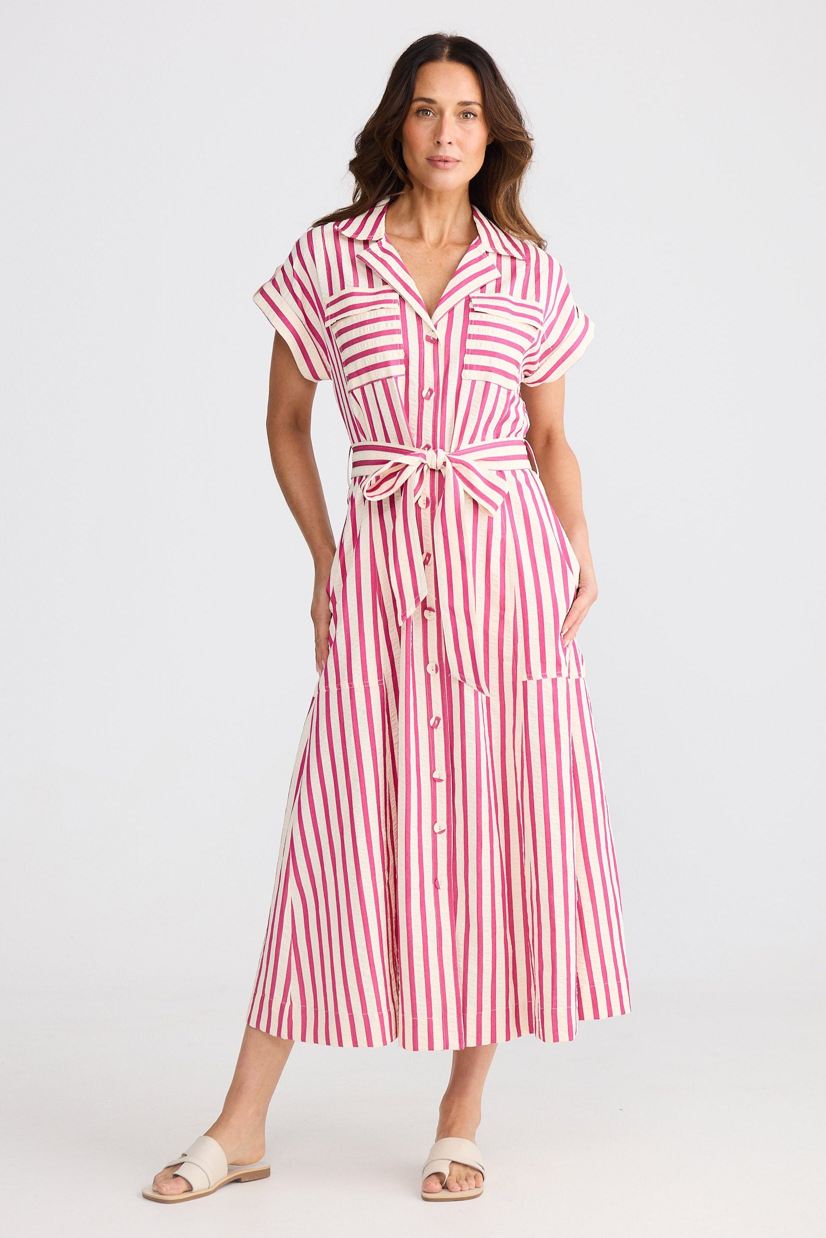 Woman wearing a hot pink and white striped dress on a white background