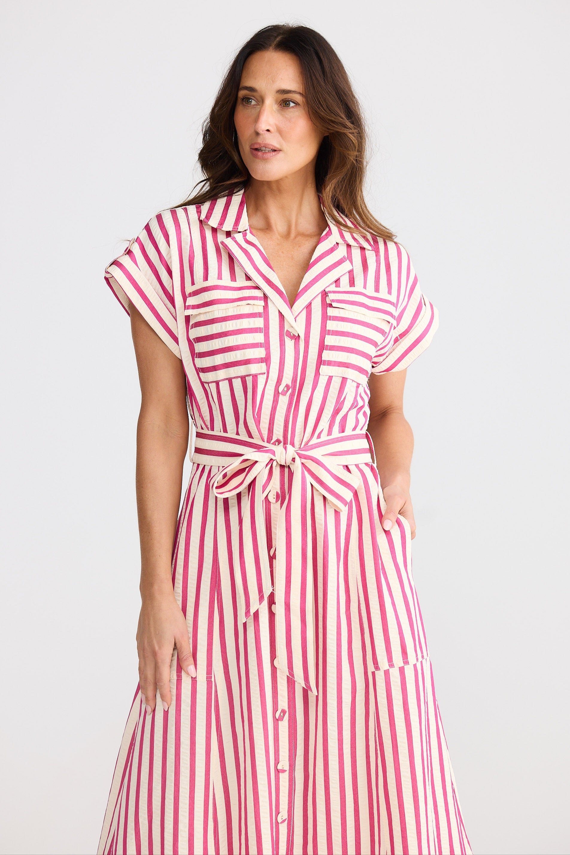 Woman wearing a hot pink and white striped dress on a plain background