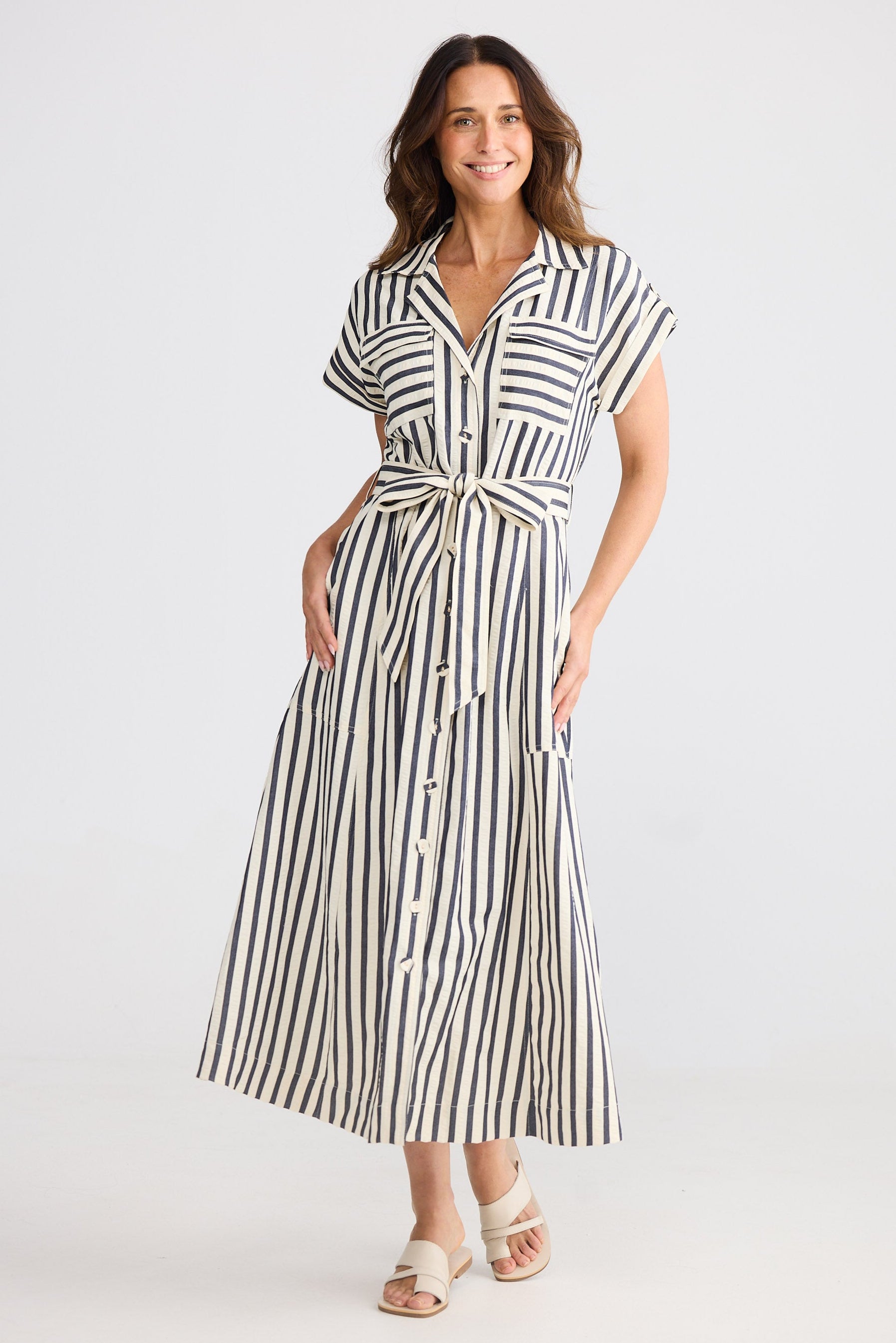 Woman wearing a navy and white striped dress on a white background