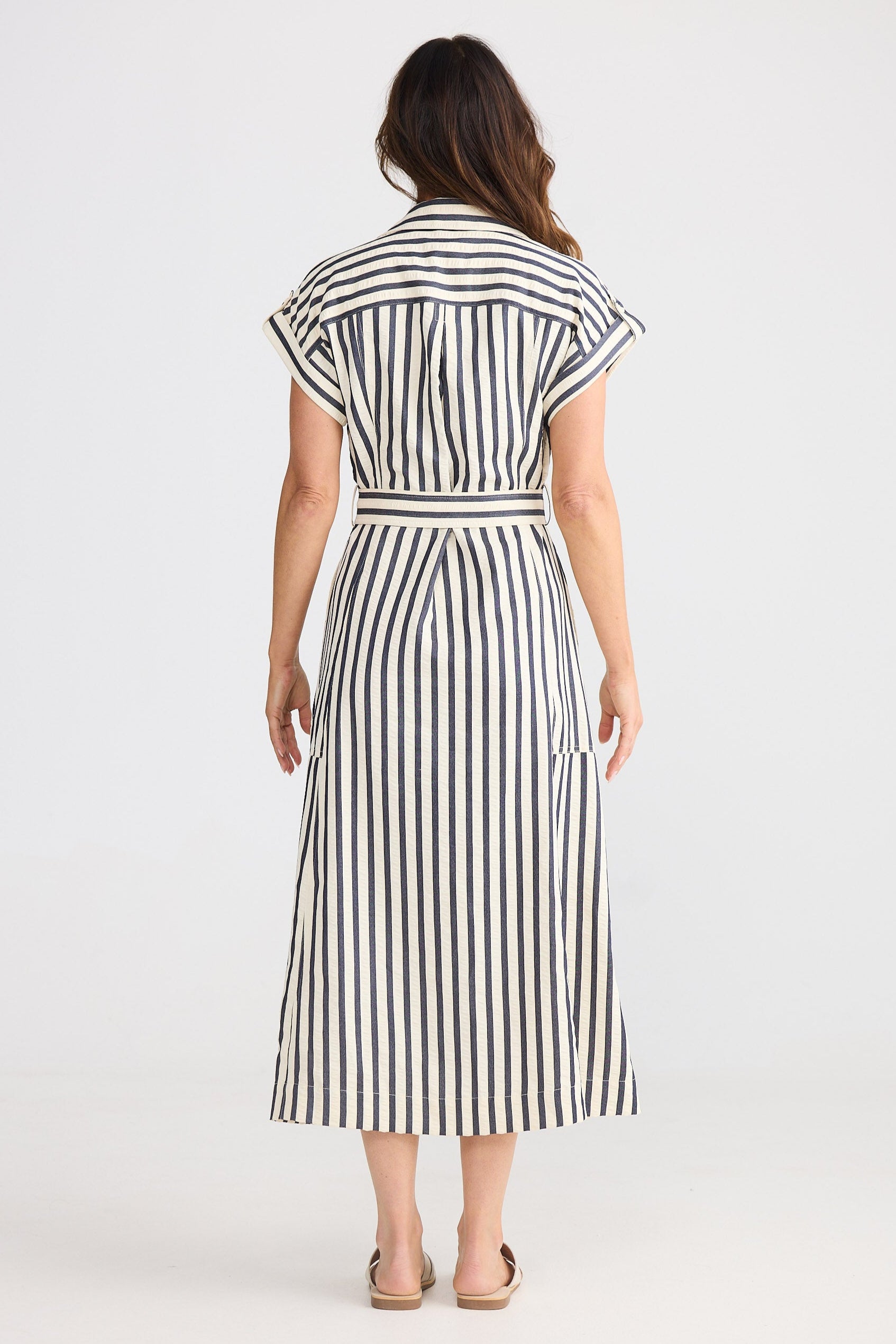 Woman wearing a navy and white striped dress on a white background