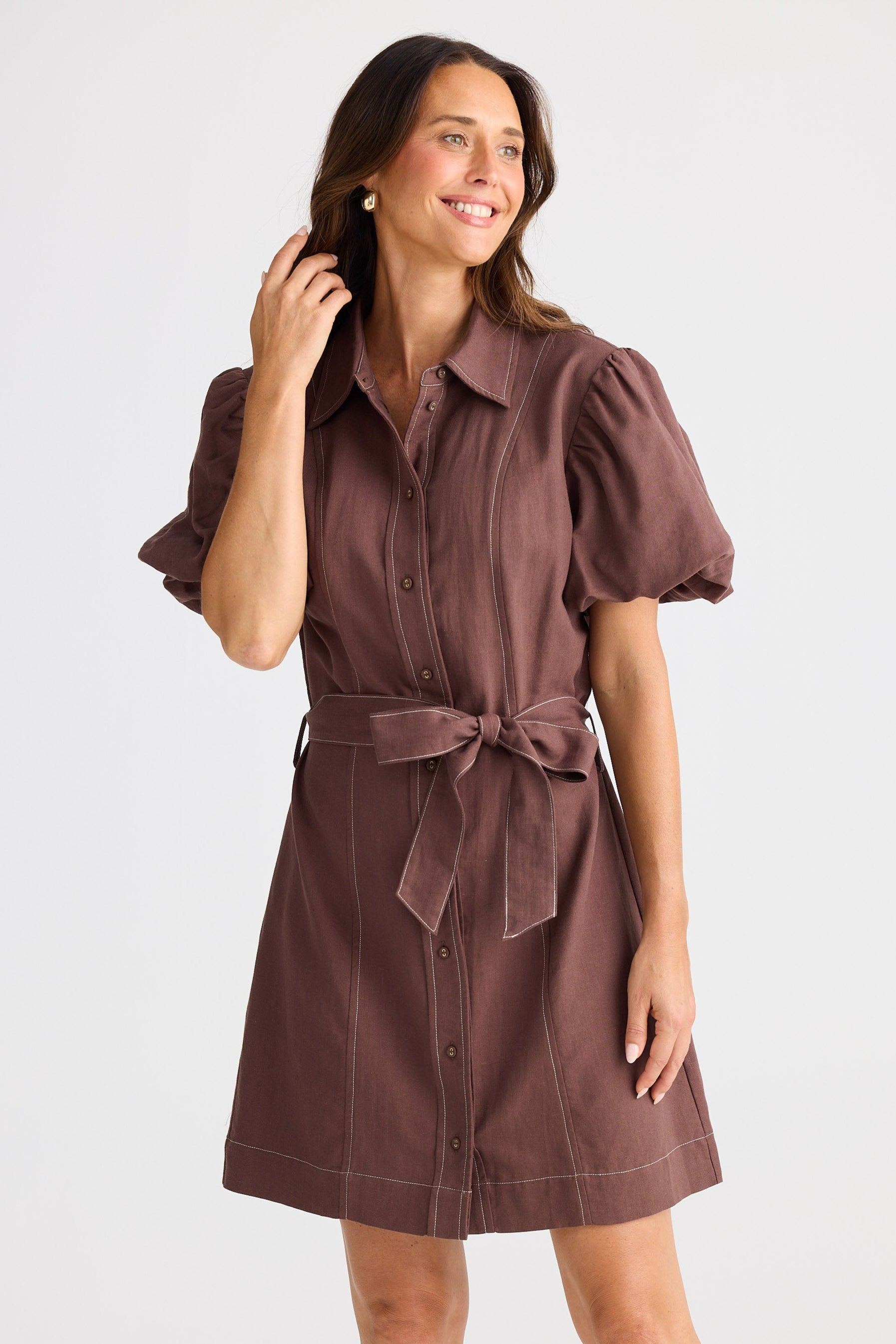 Woman wearing a brown dress with a belt on a white background