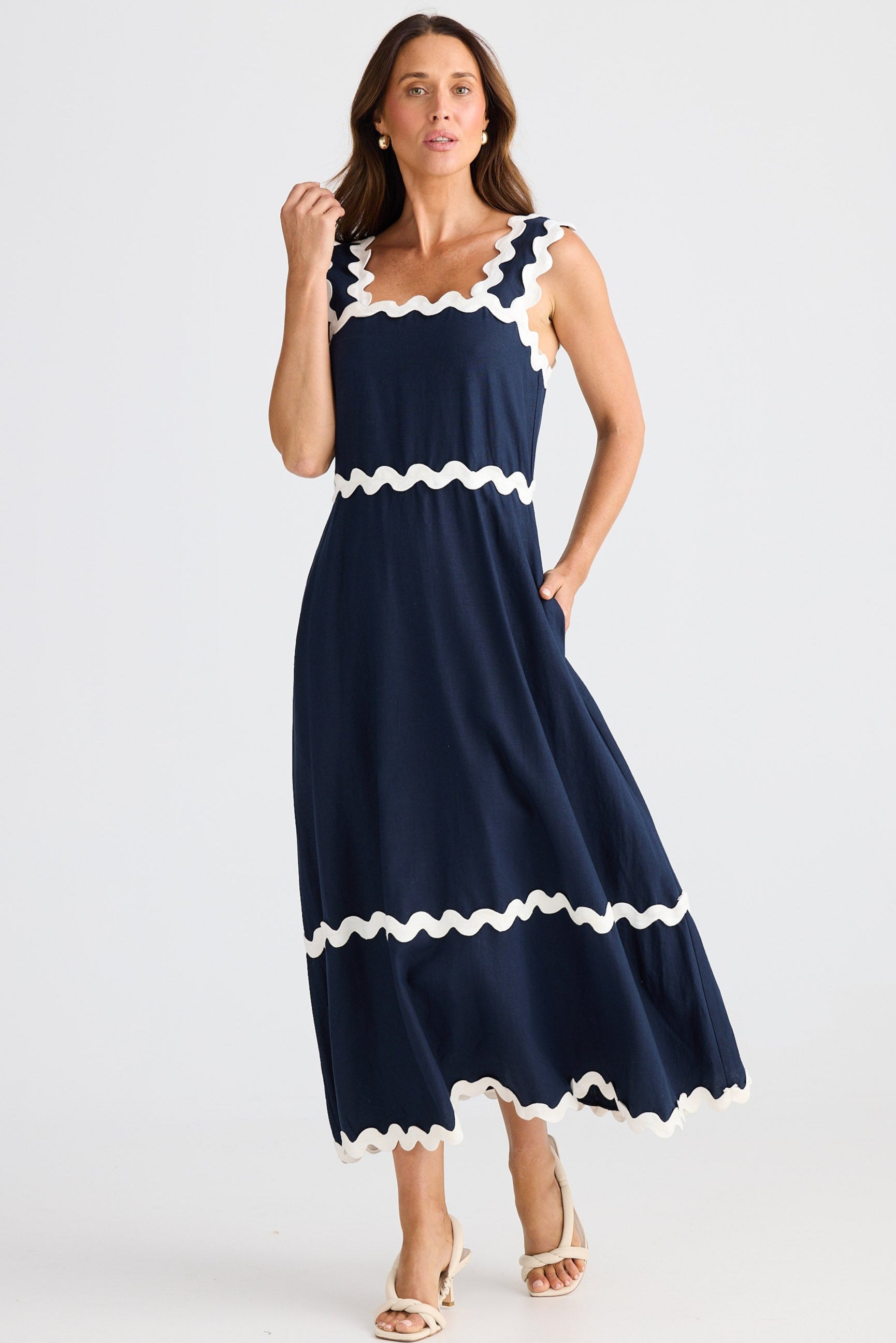 Woman wearing a navy dress with white trim on a white background