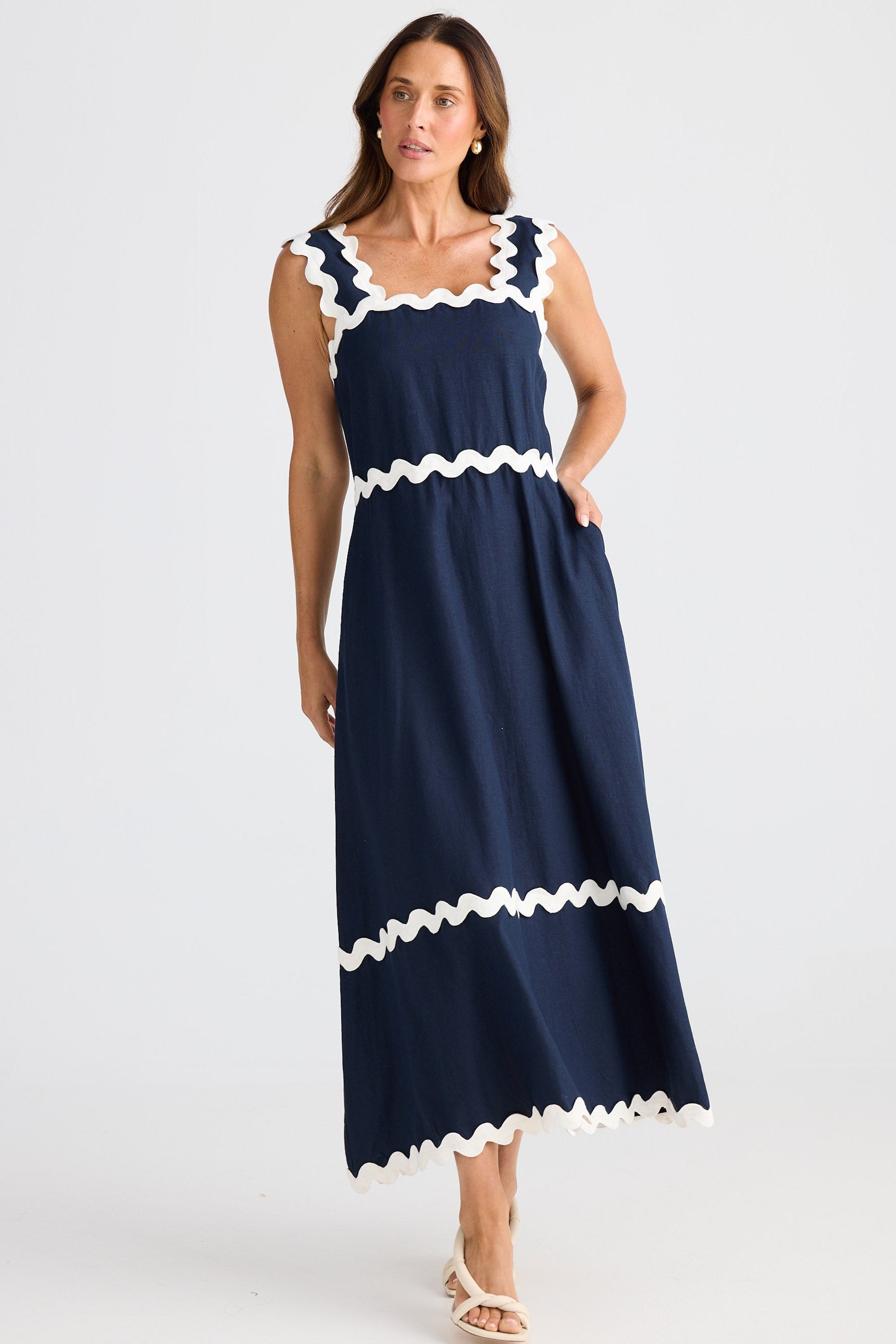Woman wearing a navy dress with white trim on a white background