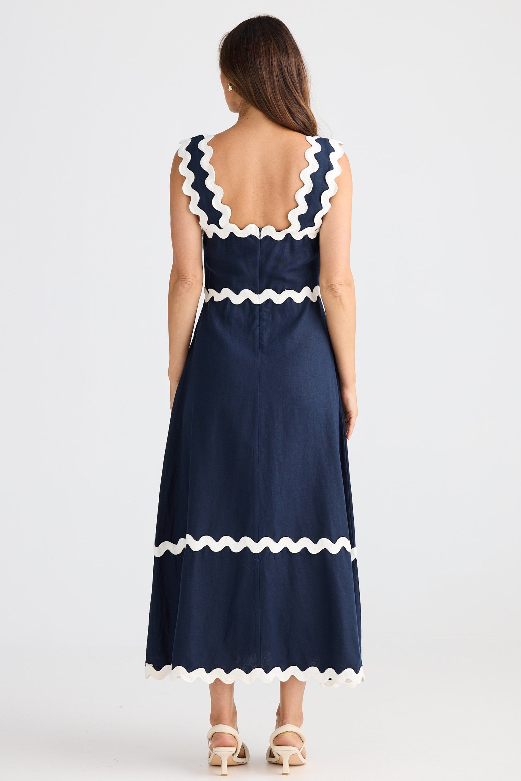 Navy dress with white ruffle details on a white background