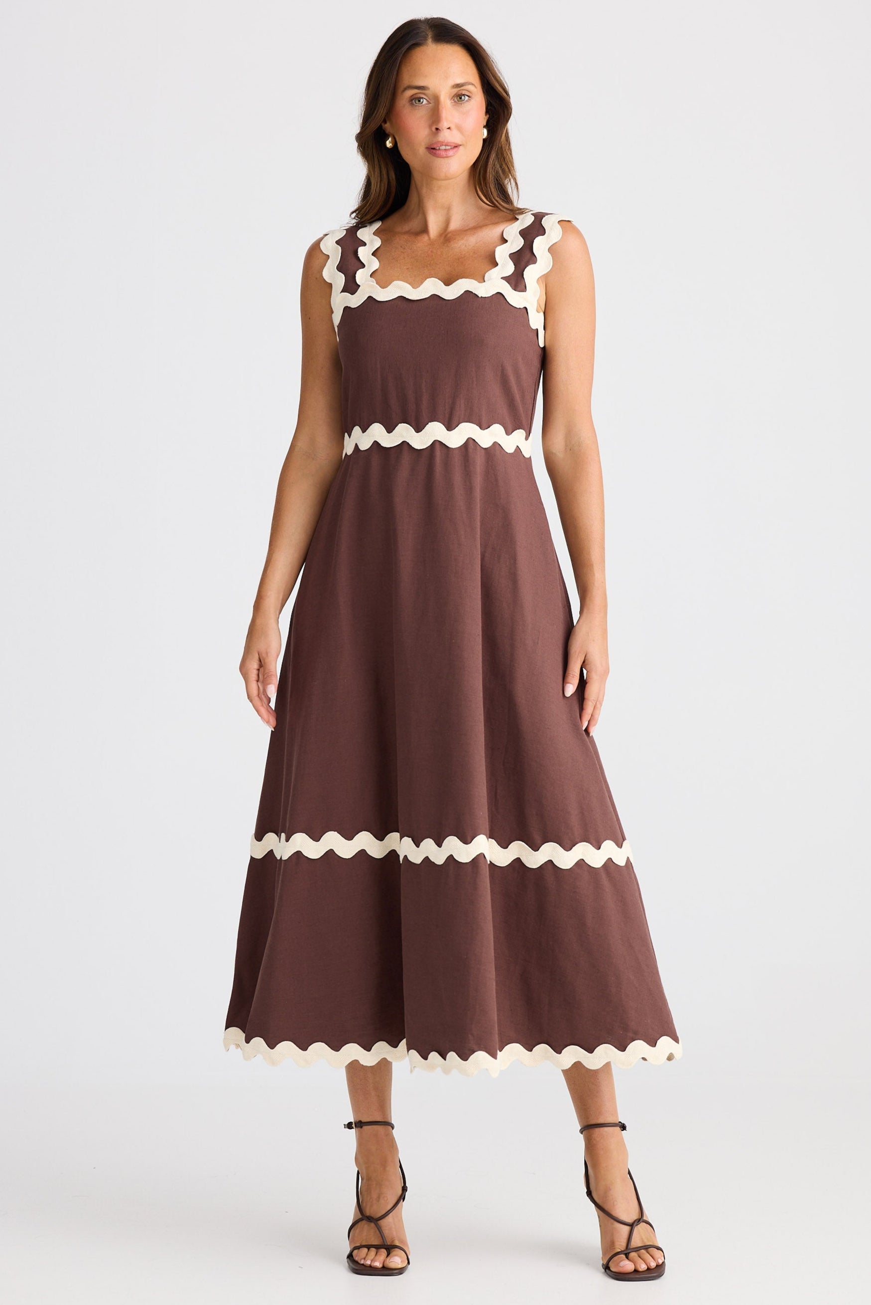 Woman wearing a brown dress with white trim on a white background
