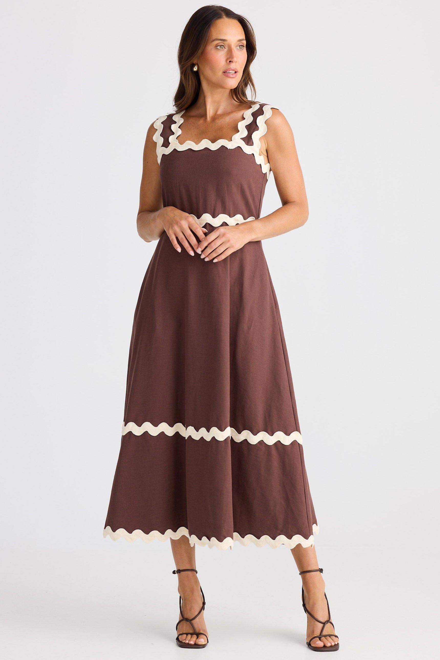 Woman wearing a brown dress with white trim on a white background