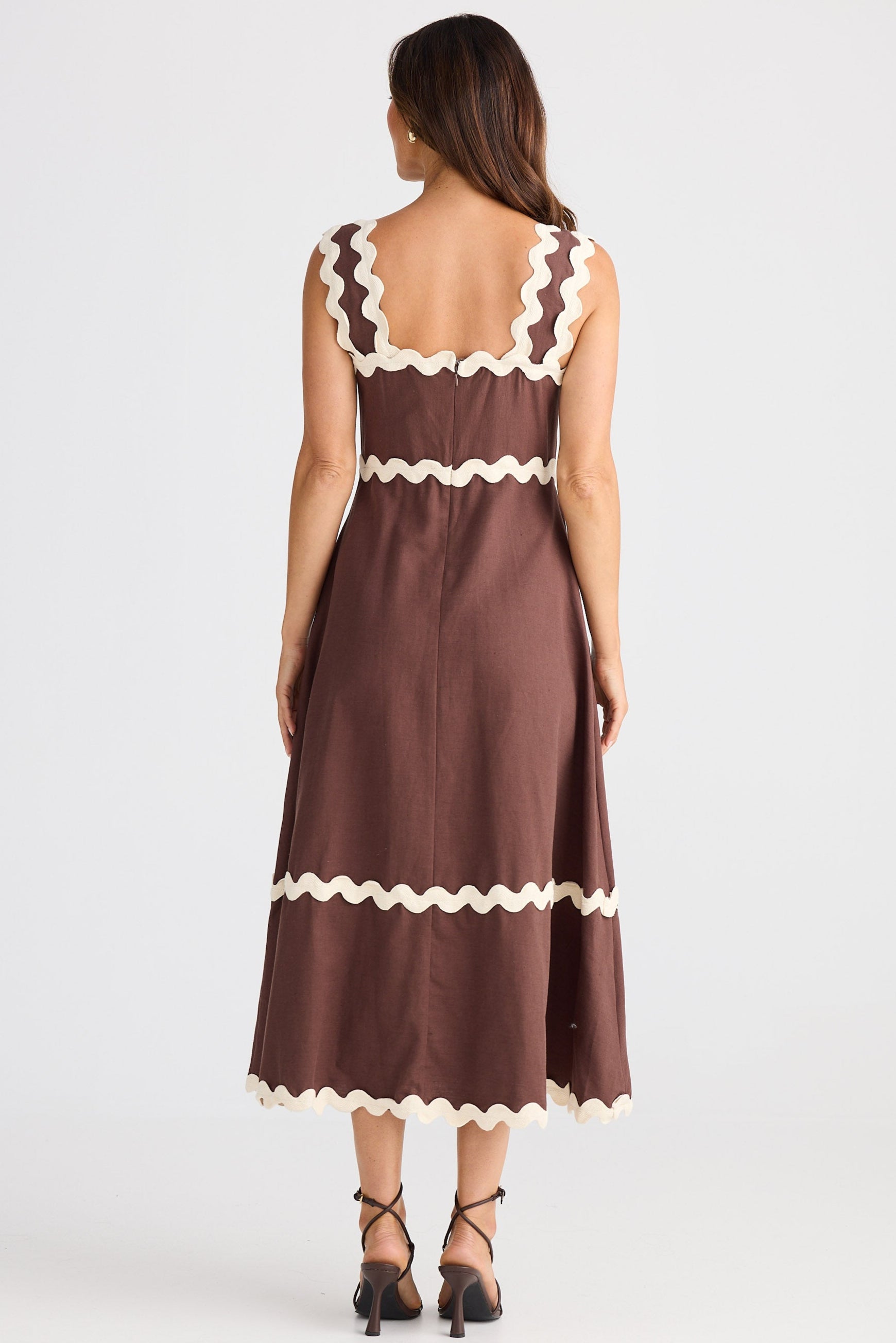 Woman wearing a brown dress with white trim on a white background
