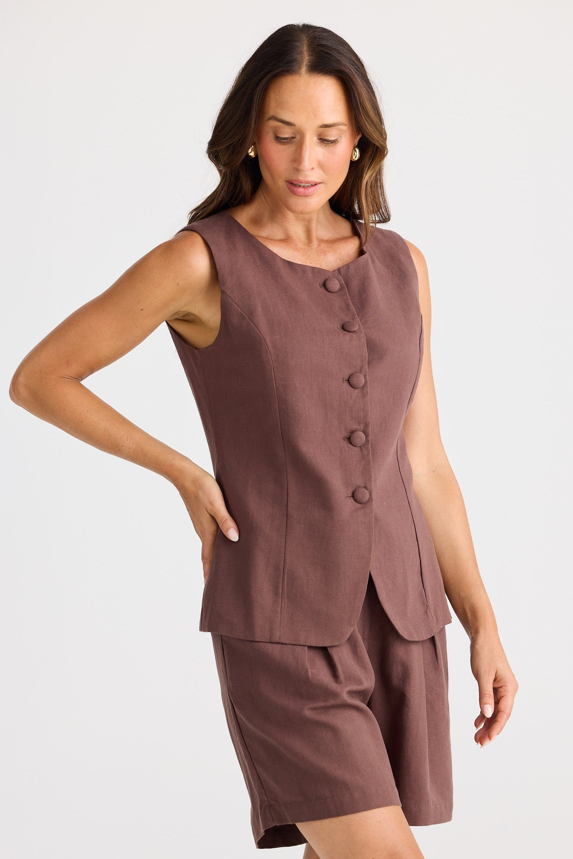Woman wearing a brown sleeveless top and shorts set on a white background