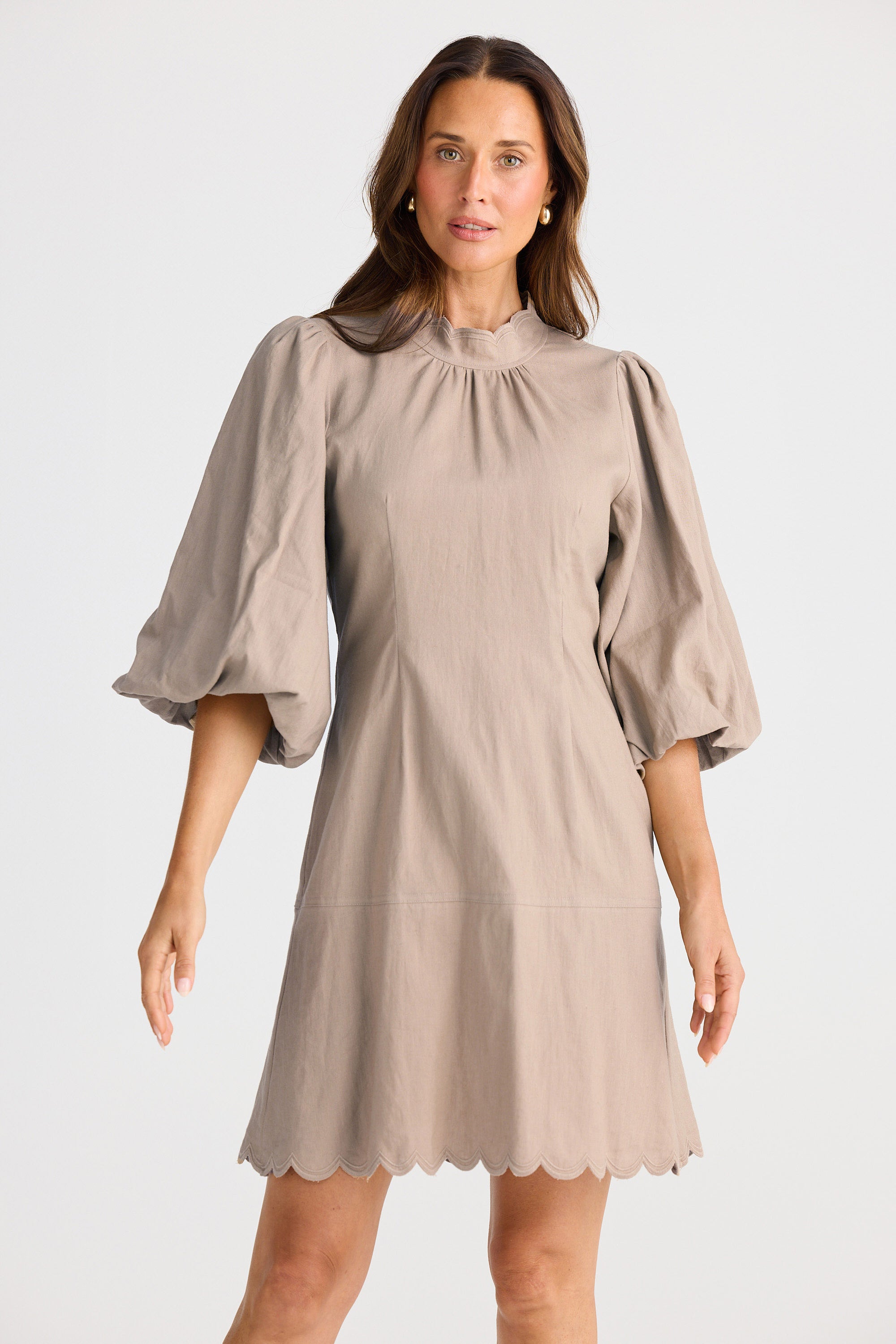 Woman wearing a beige dress with puffed sleeves on a white background