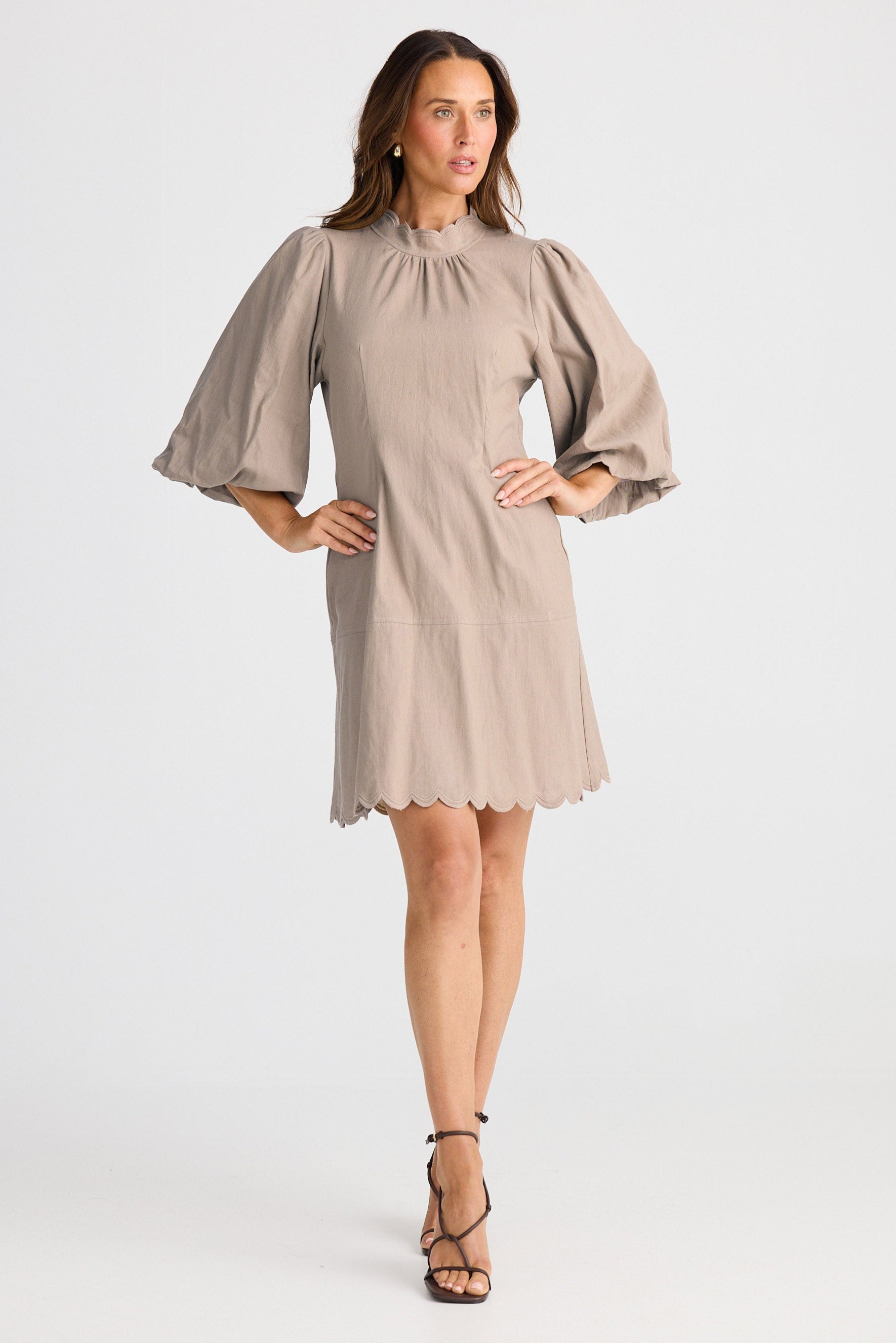 Woman wearing a beige dress with puff sleeves on a white background