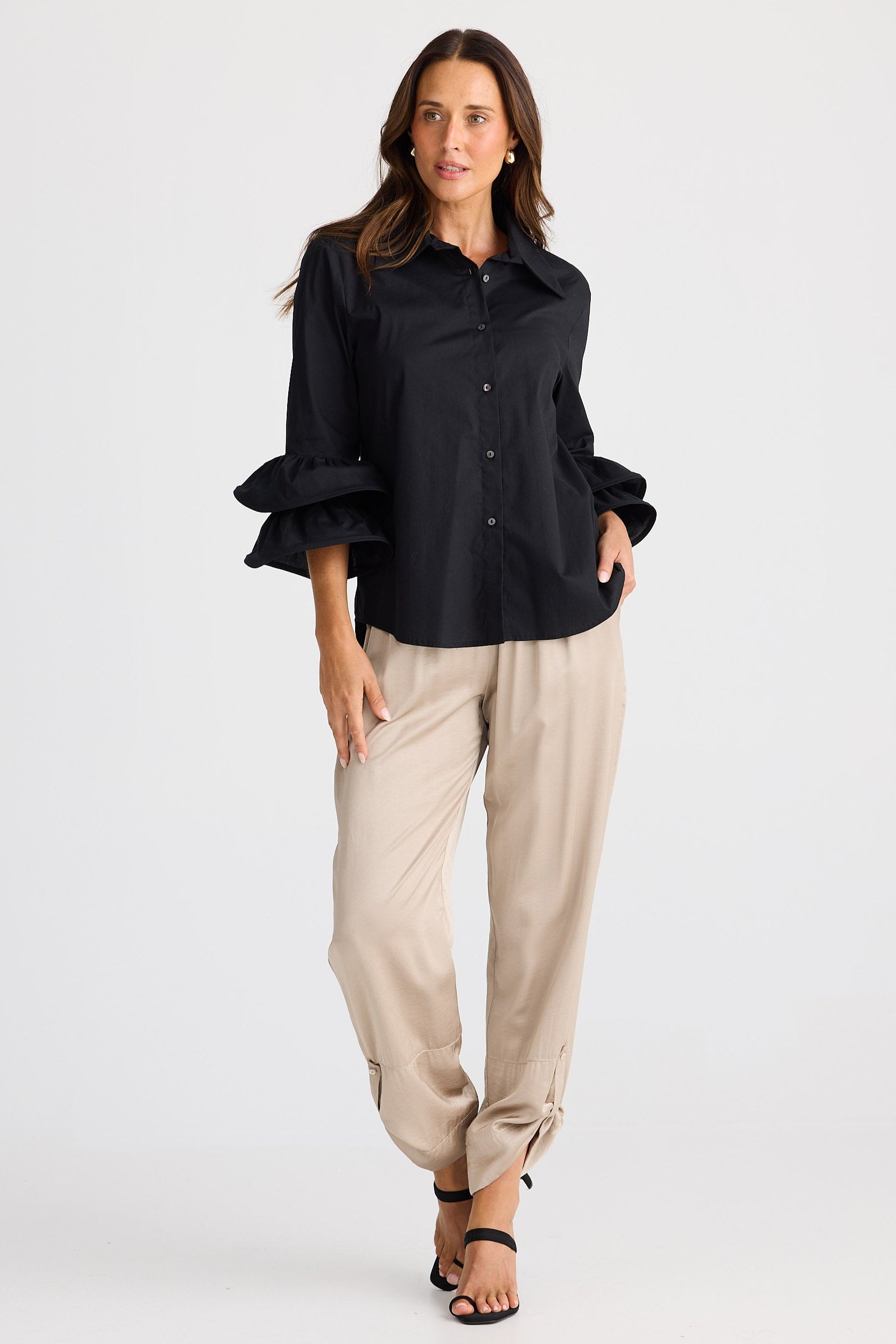 Woman wearing a black shirt and beige pants on a white background