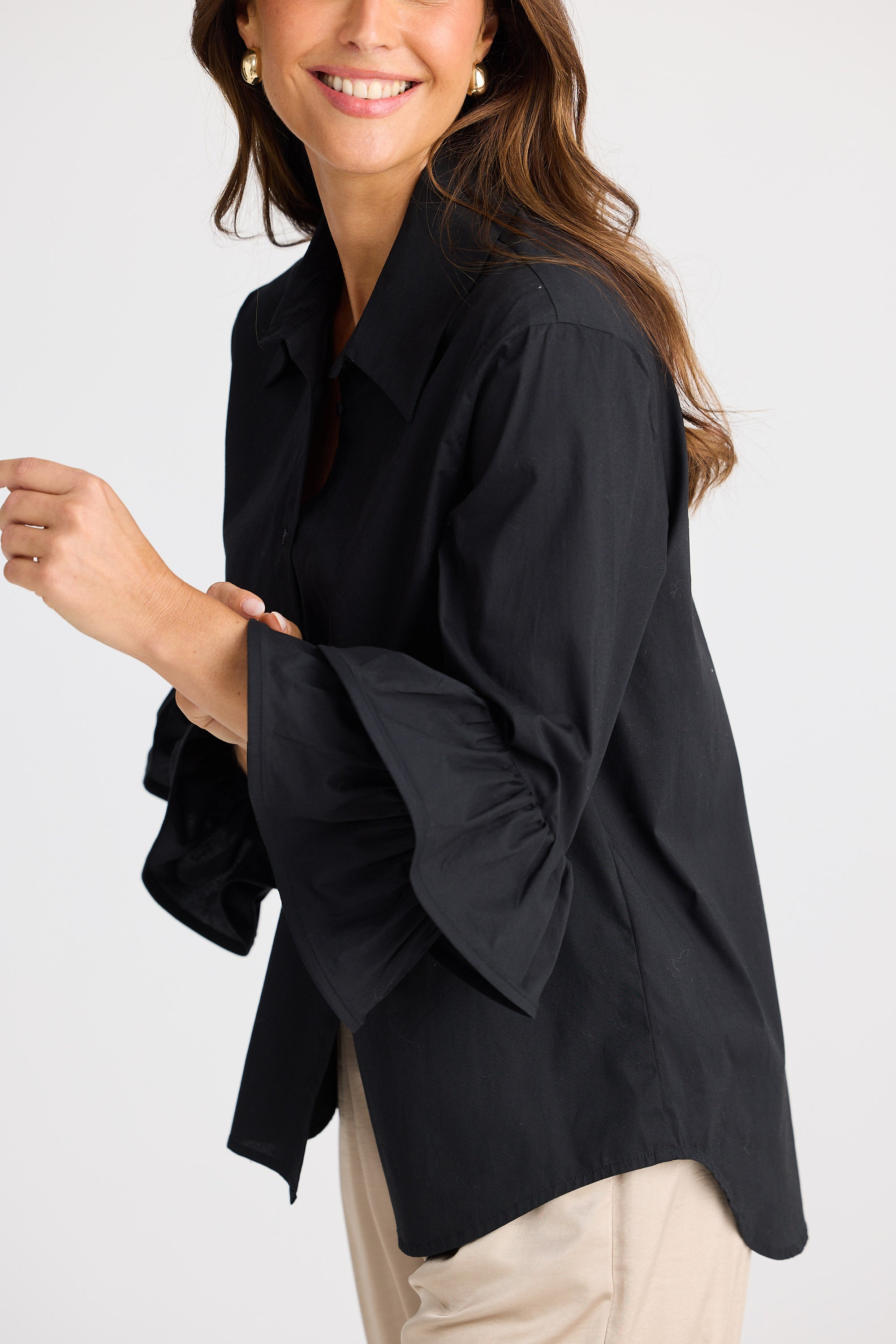 Woman wearing a black blouse with a plain background