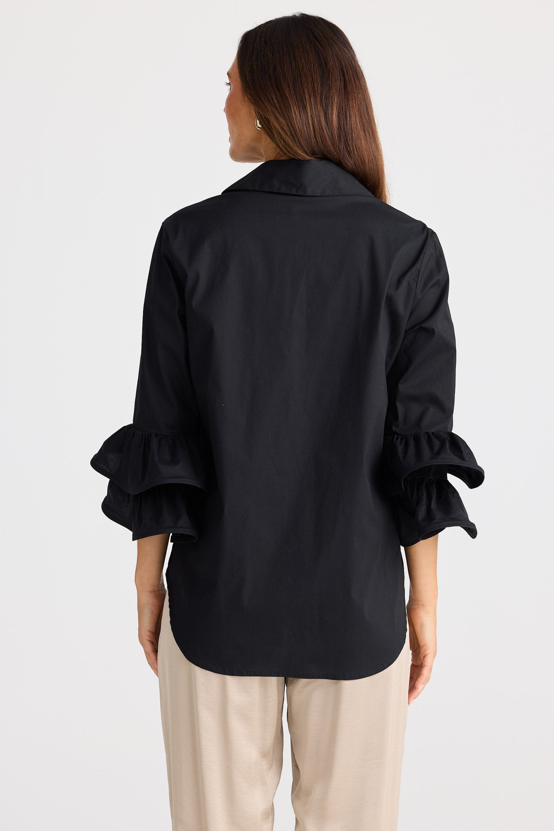 Woman wearing a black blouse with ruffled sleeves on a white background