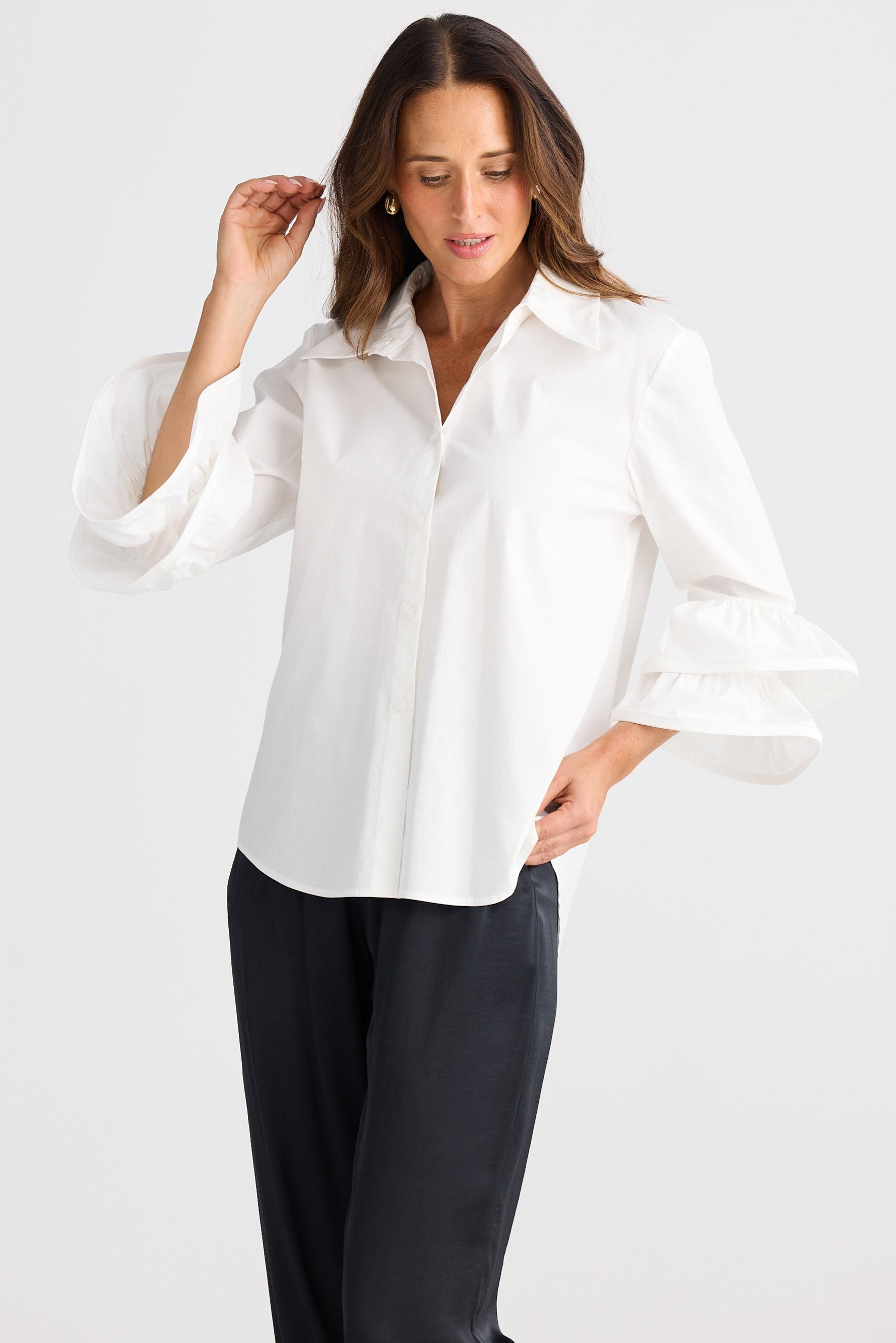 Woman wearing a white blouse and black pants on a white background