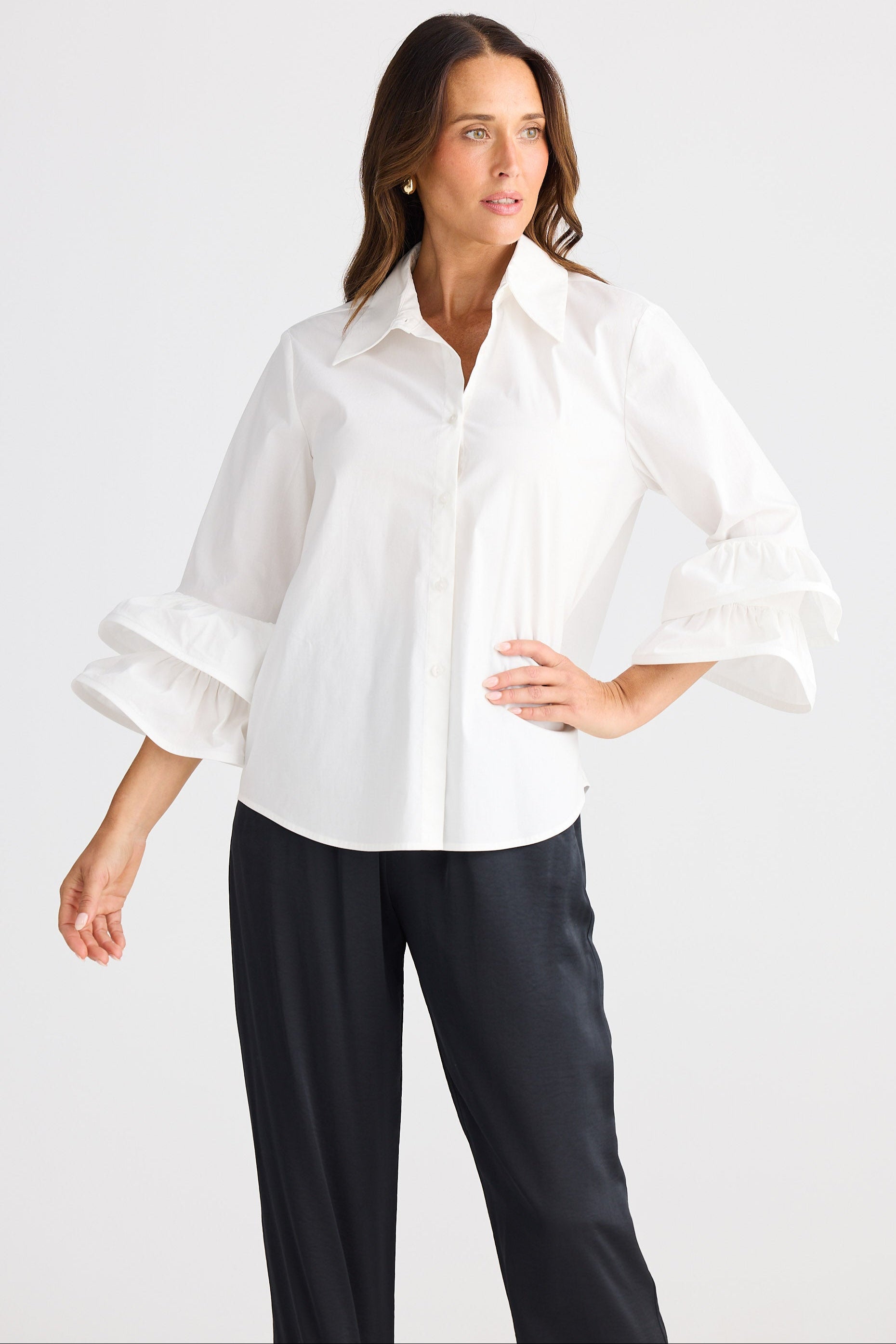Woman wearing a white blouse and black pants on a light gray background