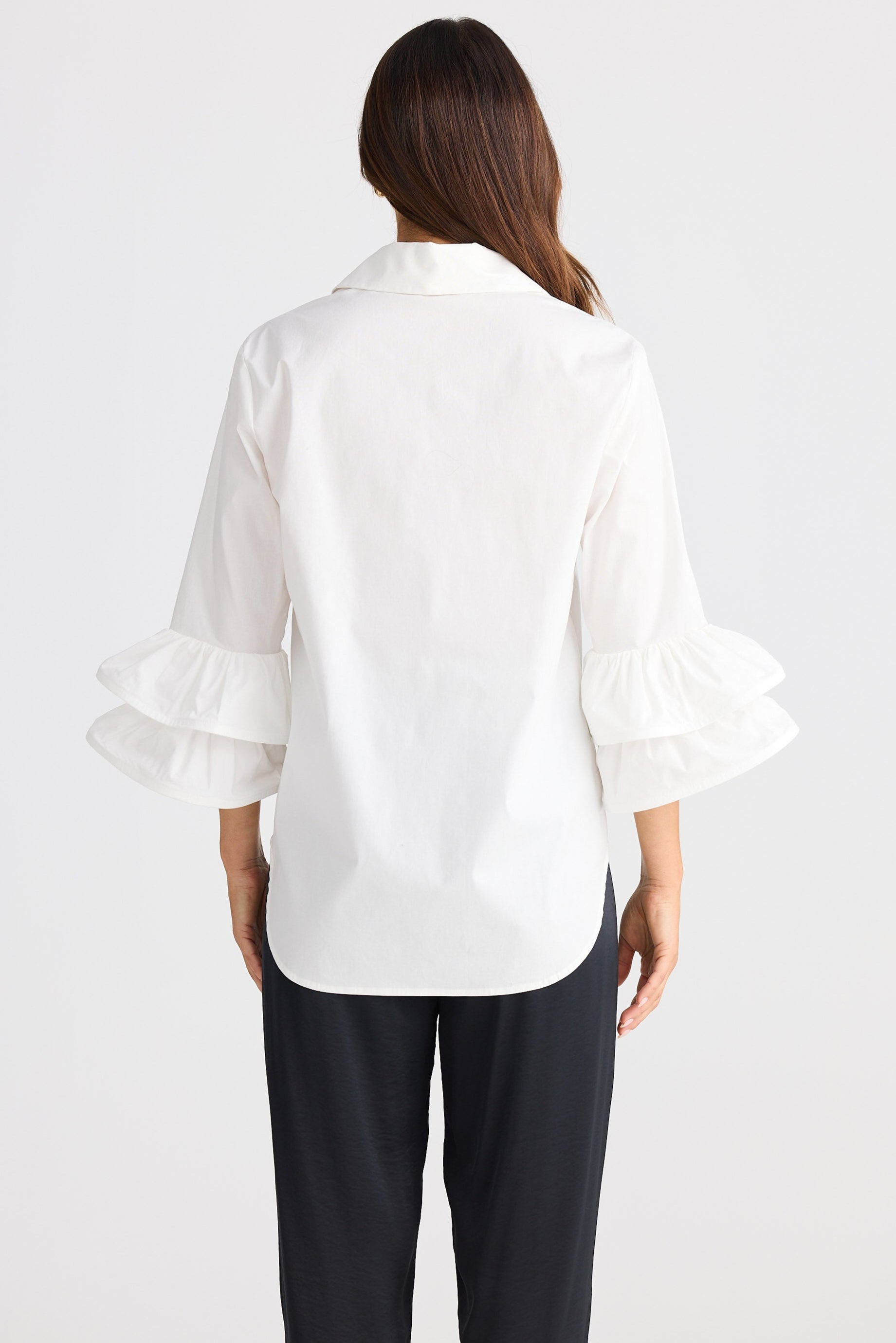 Woman wearing a white blouse with ruffled sleeves on a white background