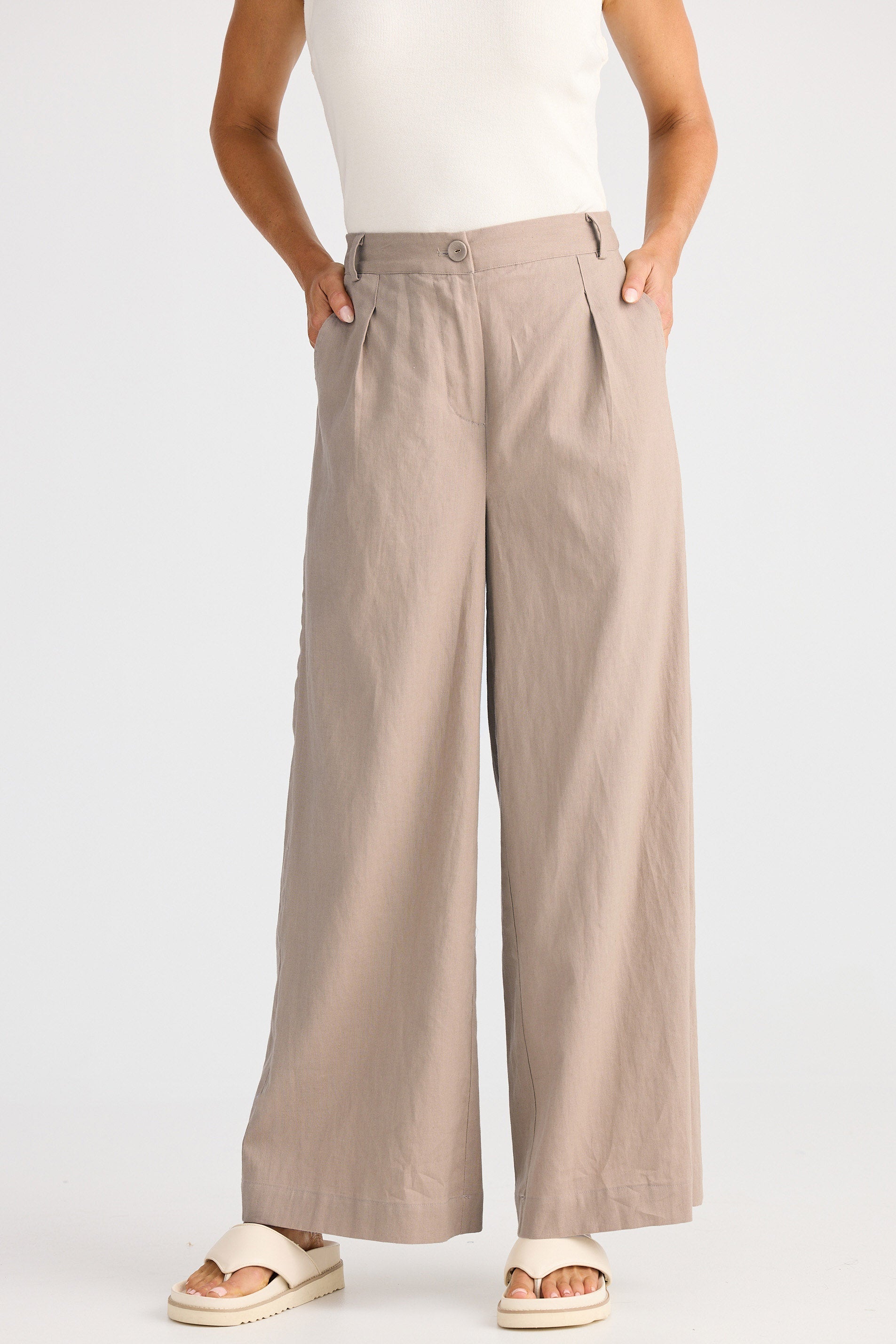 Person wearing beige wide-leg pants on a white background