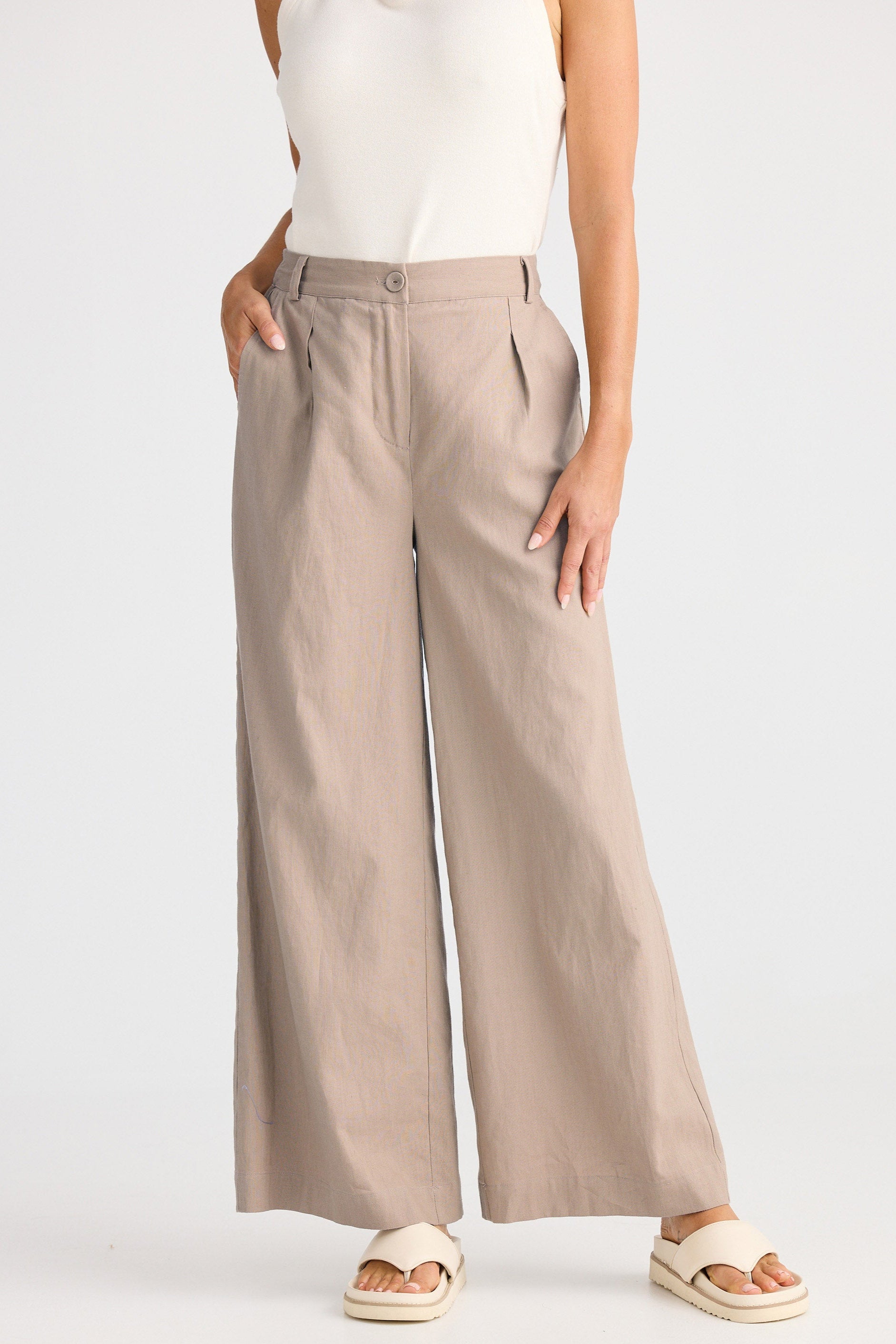 Person wearing beige wide-leg pants on a white background