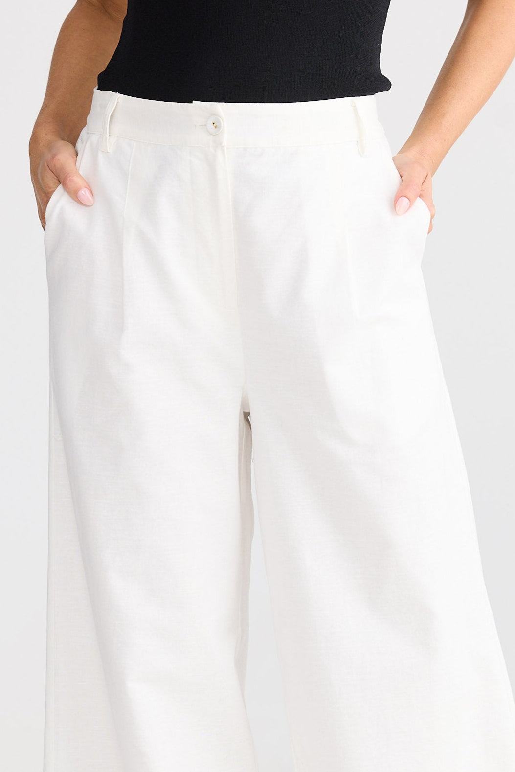 Person wearing white wide-leg pants and a black top on a white background