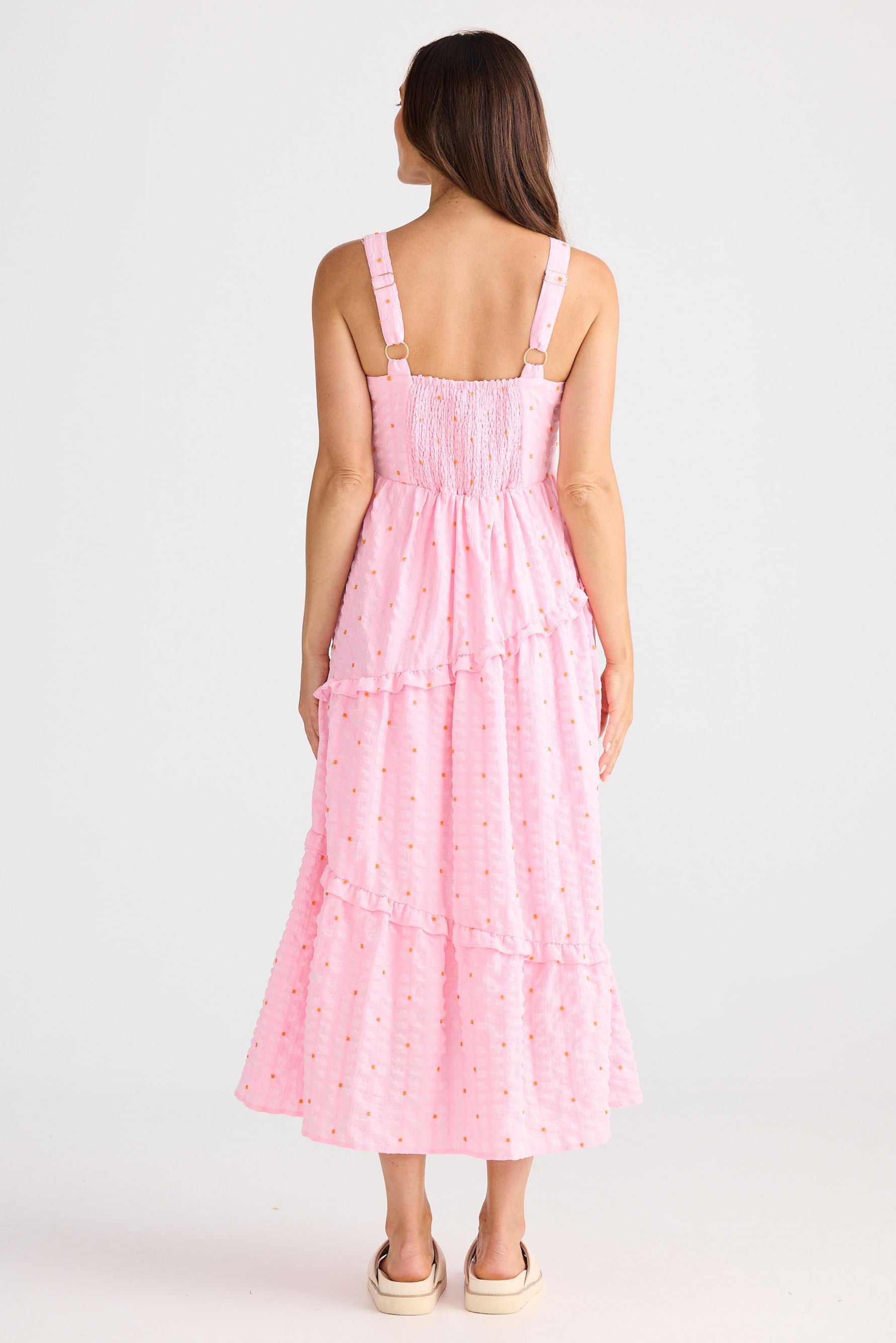 Woman wearing a pink dress with thin straps on a white background
