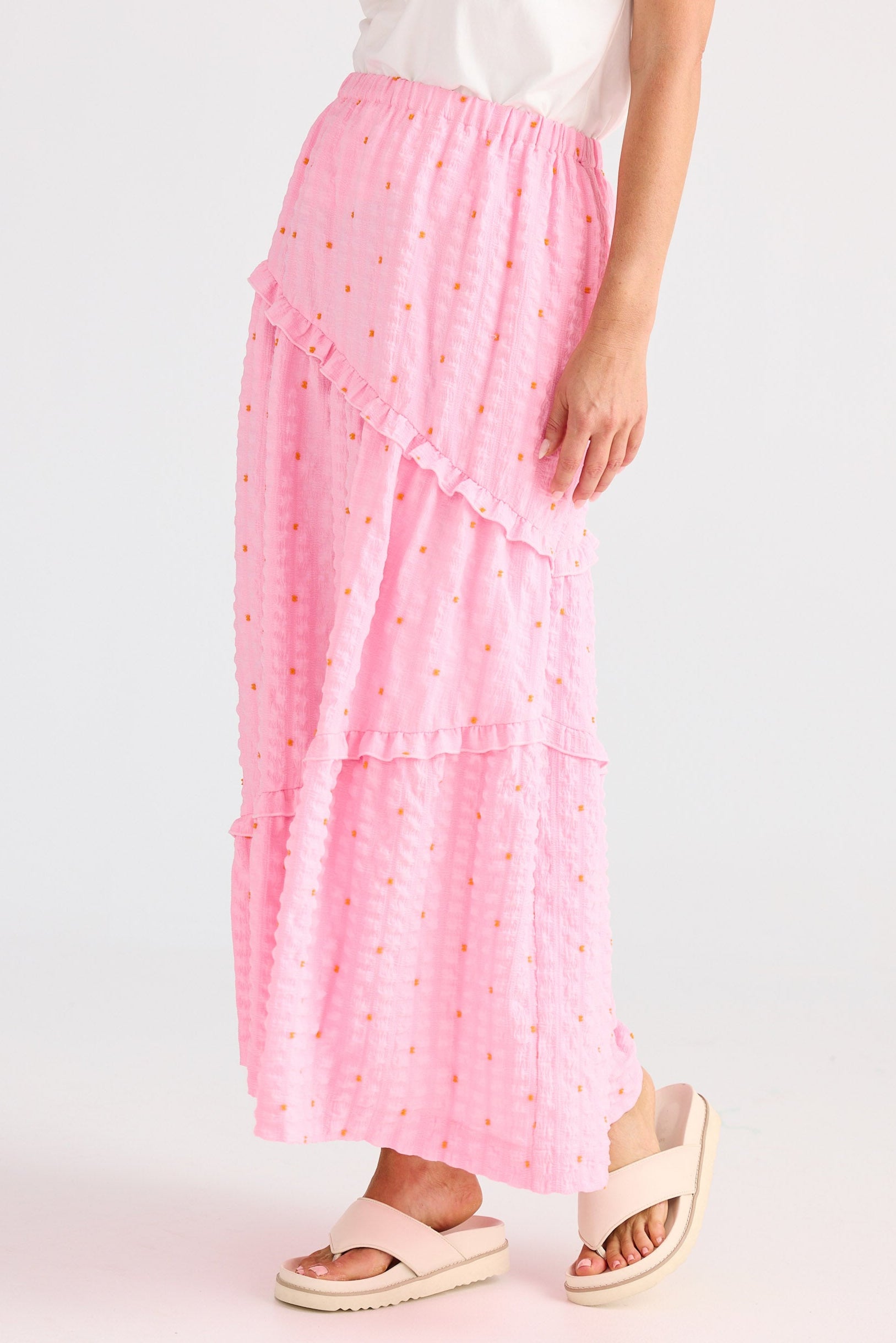 Person wearing a pink skirt with white polka dots on a light background