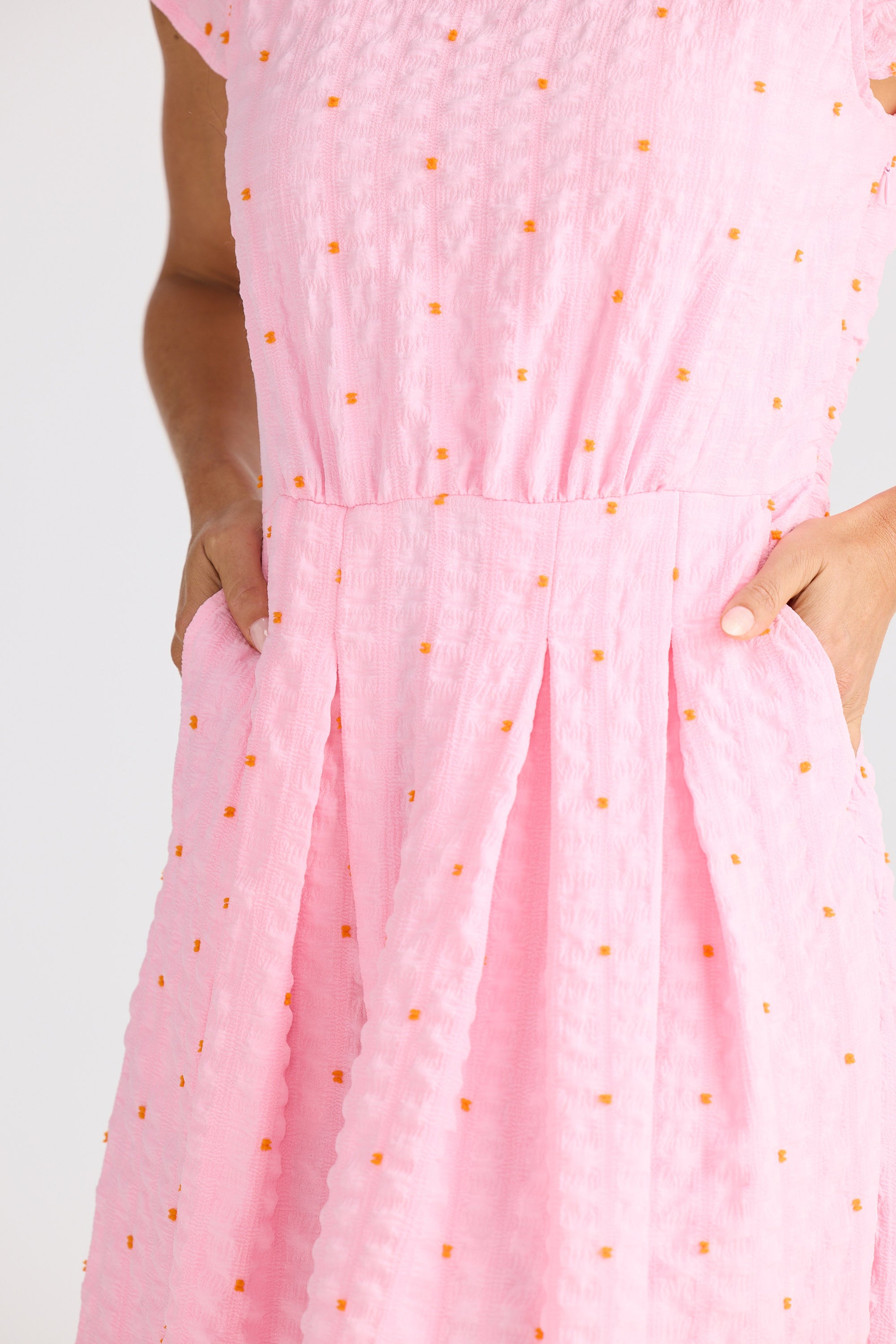 Close-up of a pink dress with gold polka dots on a white background