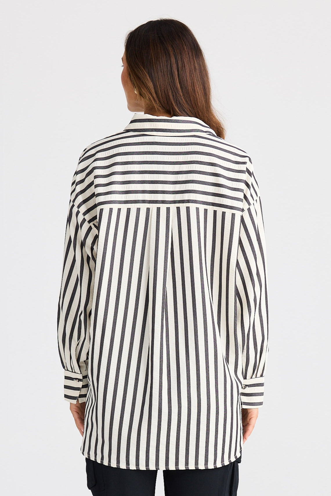 Person wearing a black and white striped shirt and black pants on a white background