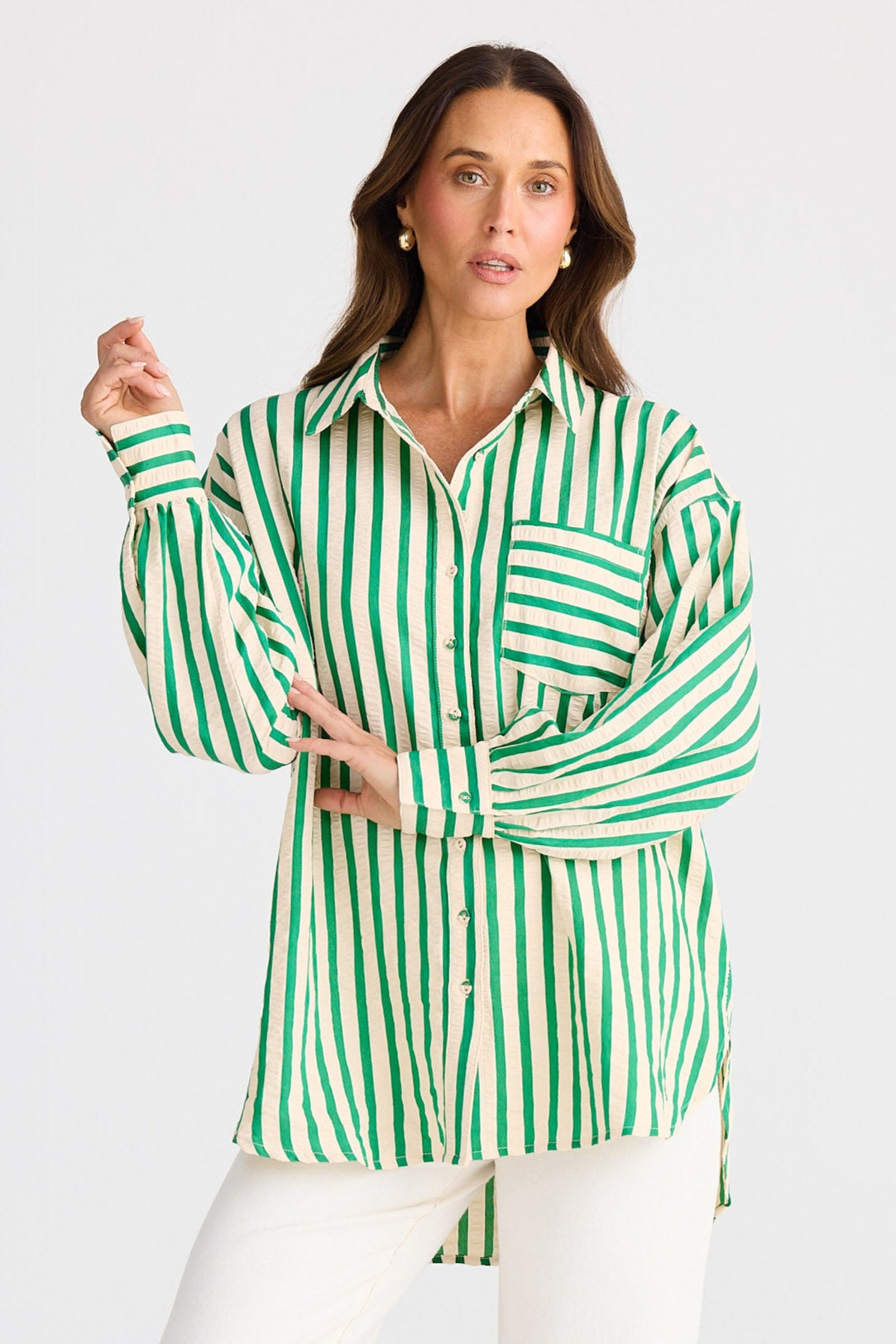 Woman wearing a green and white striped shirt with white pants on a light gray background