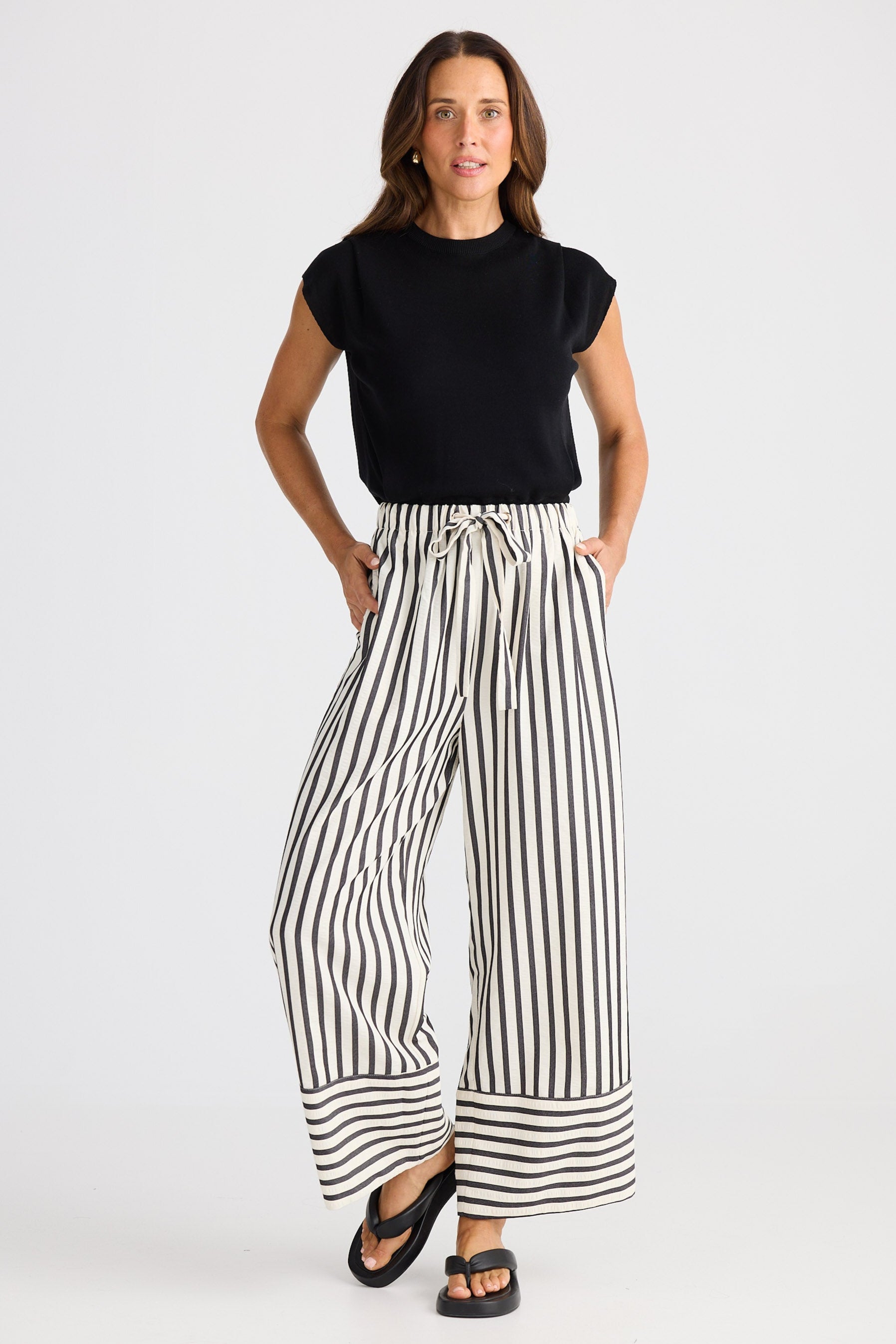 Woman wearing a black top and striped pants on a white background