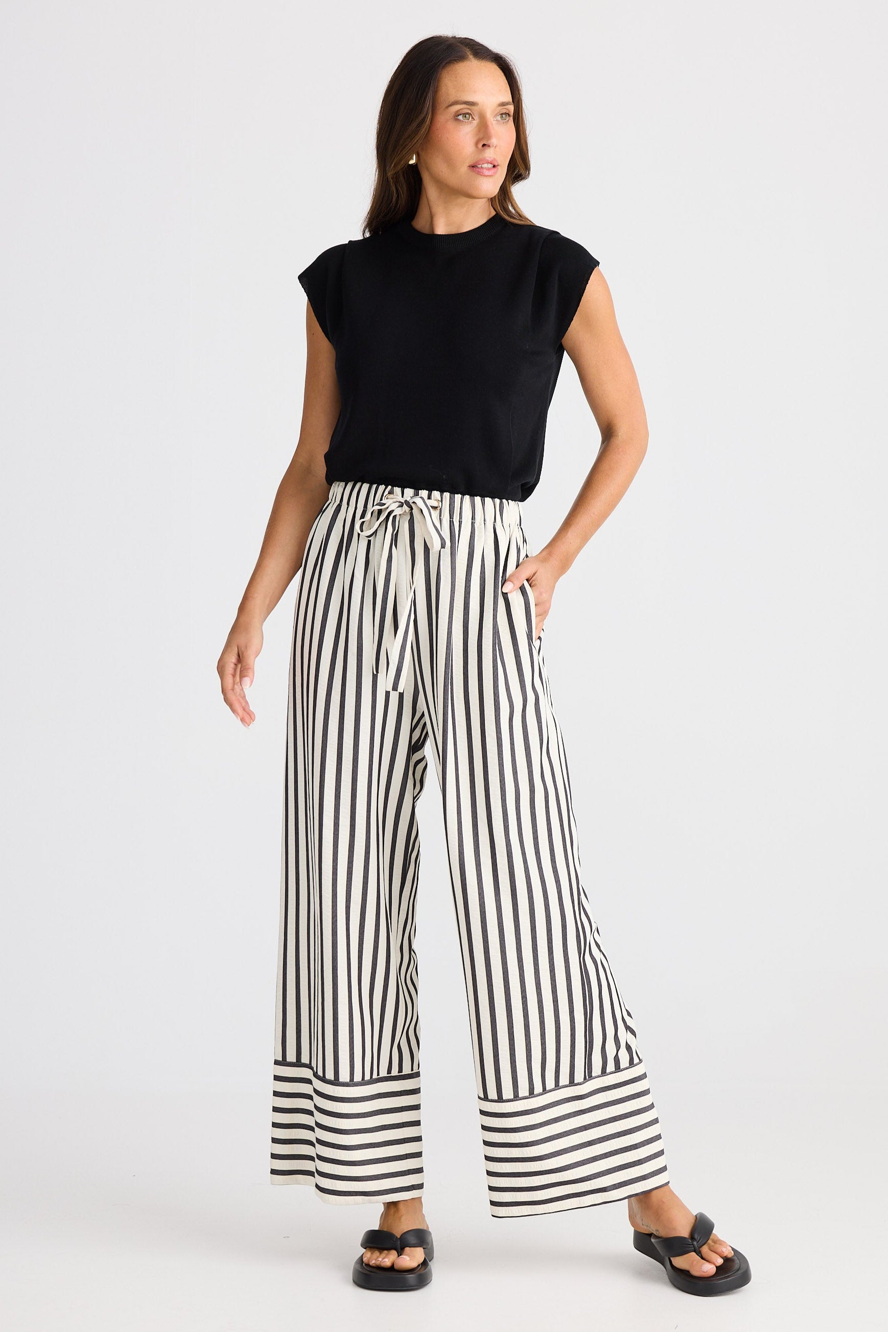 Woman wearing a black top and striped pants on a white background
