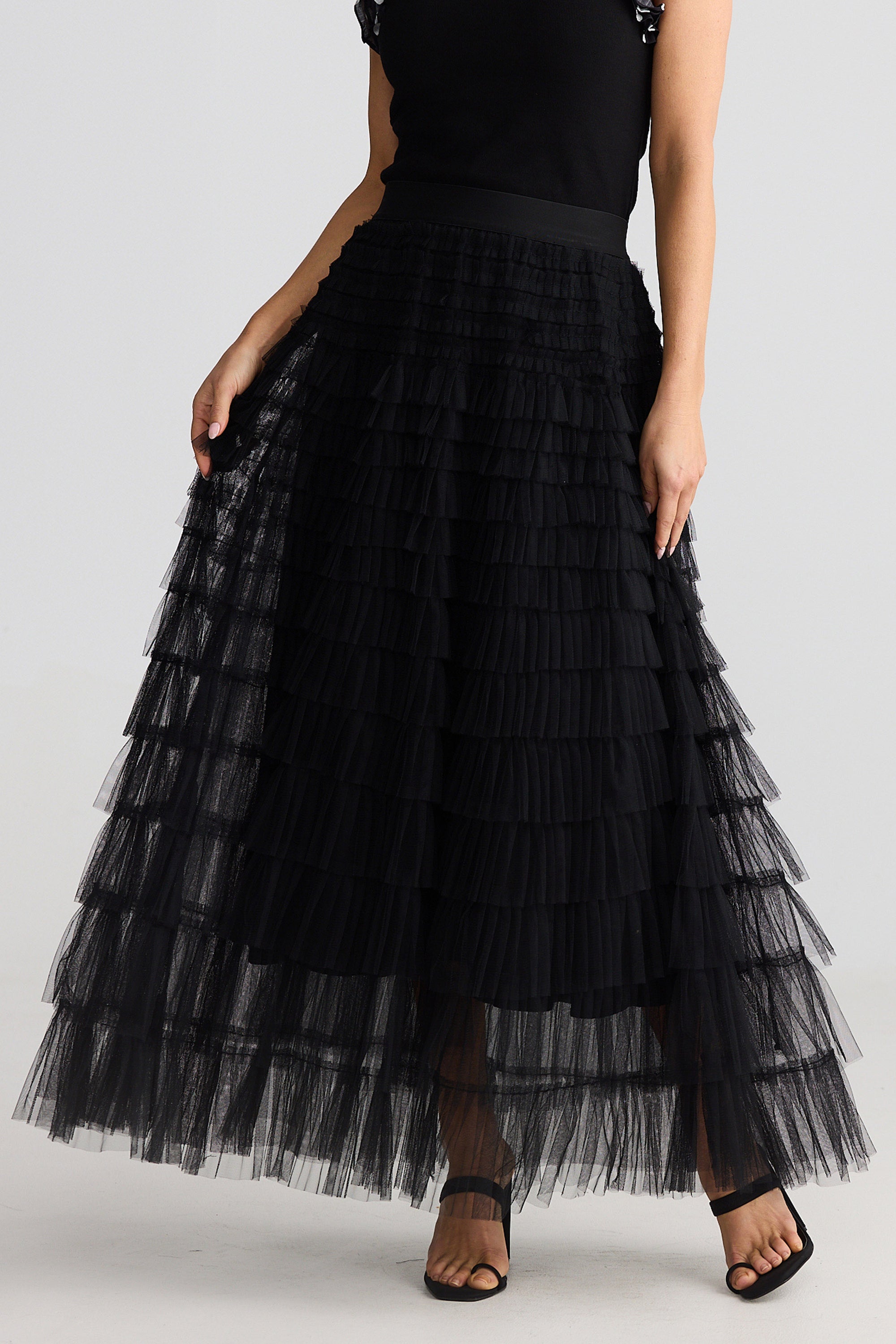 Black tiered tulle skirt worn by a person on a white background