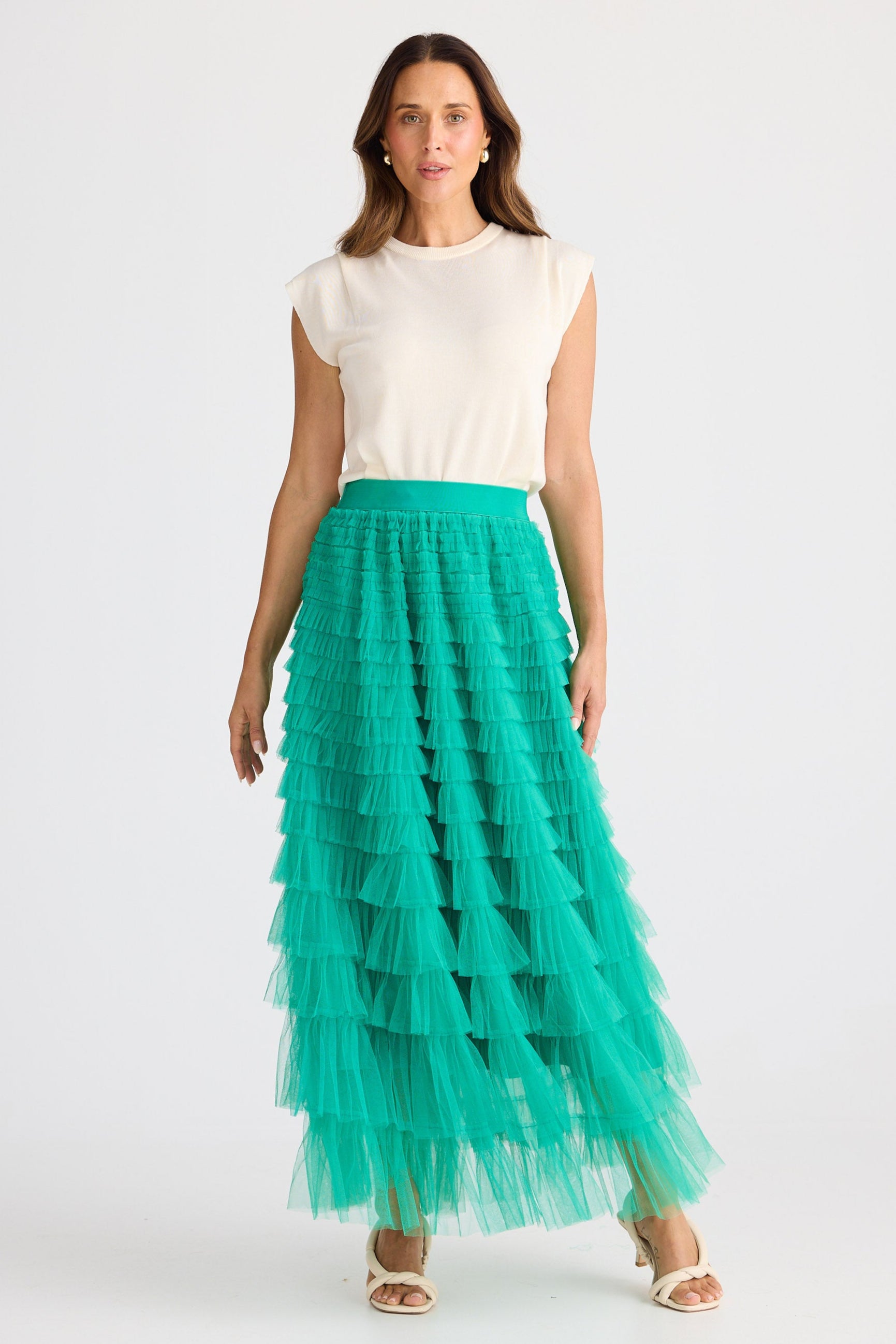 Woman wearing a white top and green tiered skirt on a white background