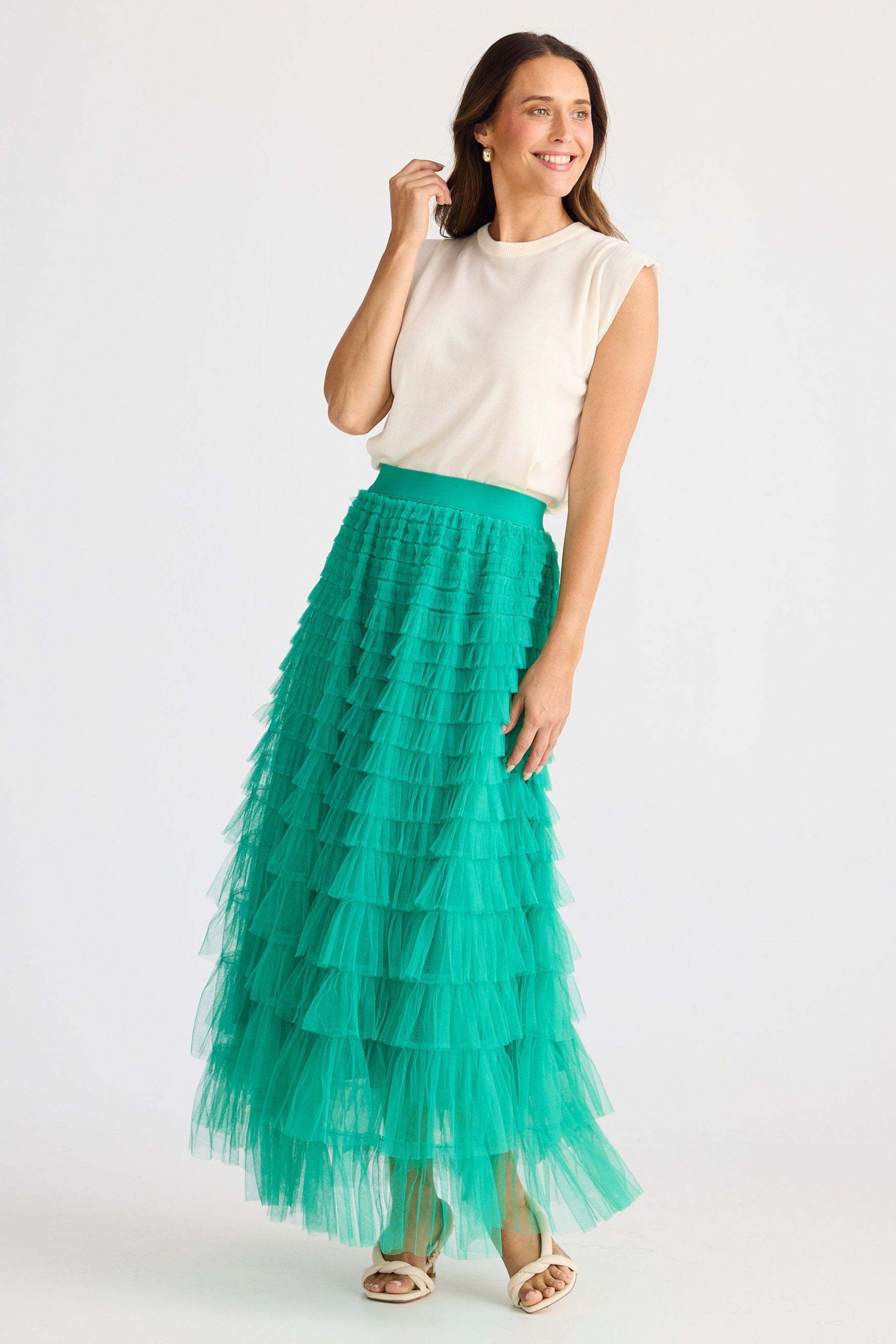 Woman wearing a white top and teal tiered skirt on a white background