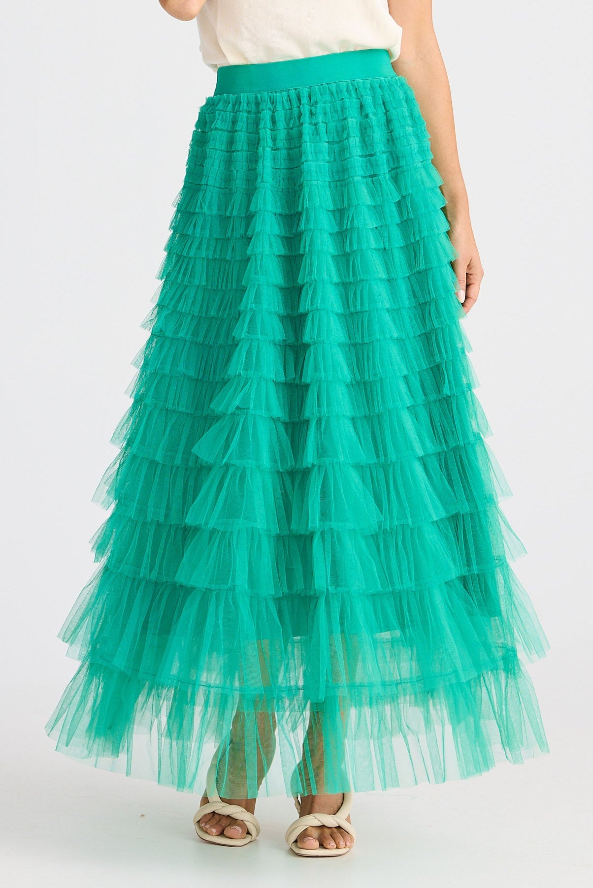 Woman wearing a white top and teal tulle skirt on a white background