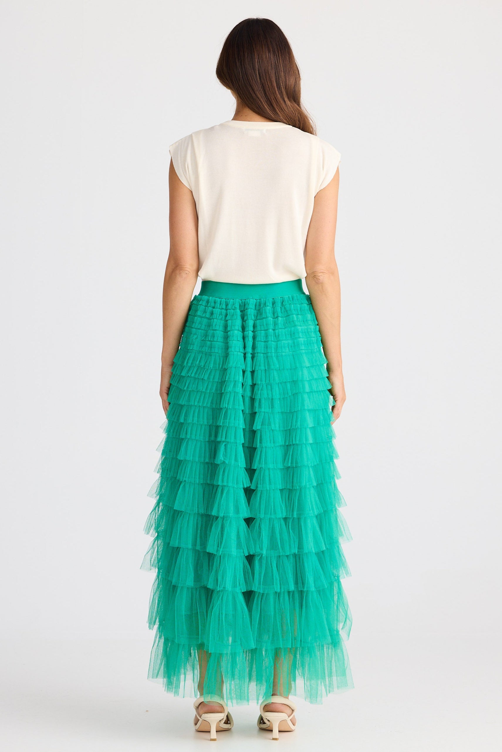 Woman wearing a white top and green tiered skirt on a white background