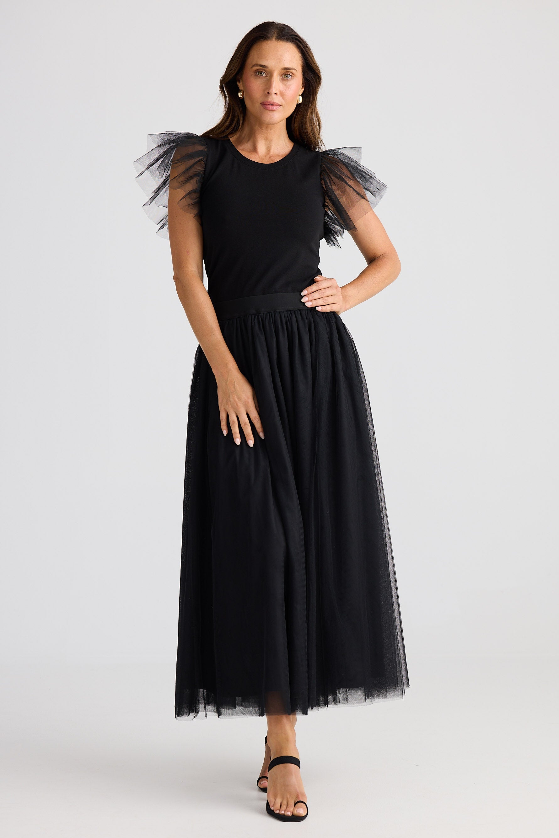Woman wearing a black dress with sheer sleeves against a white background
