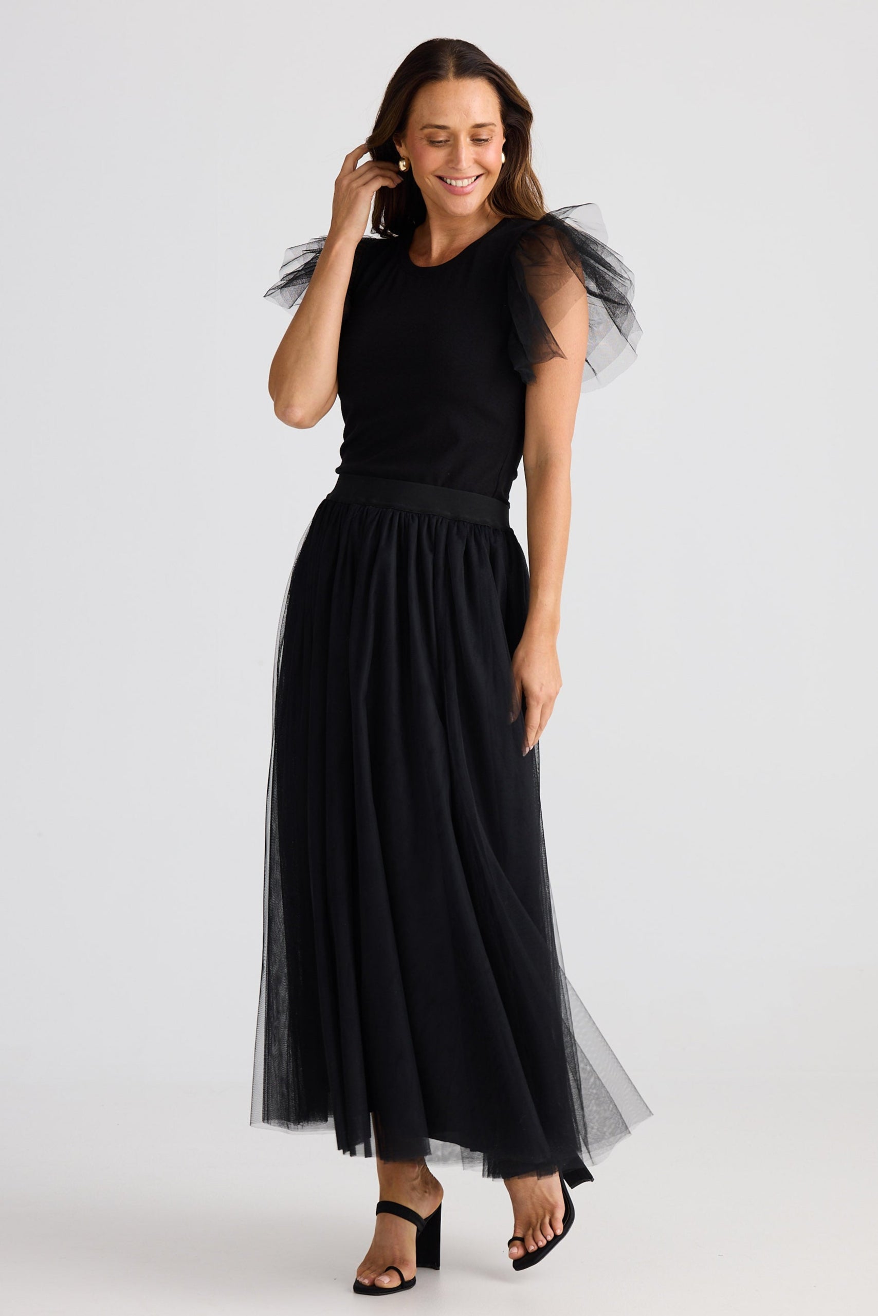 Woman wearing a black dress with sheer sleeves on a white background