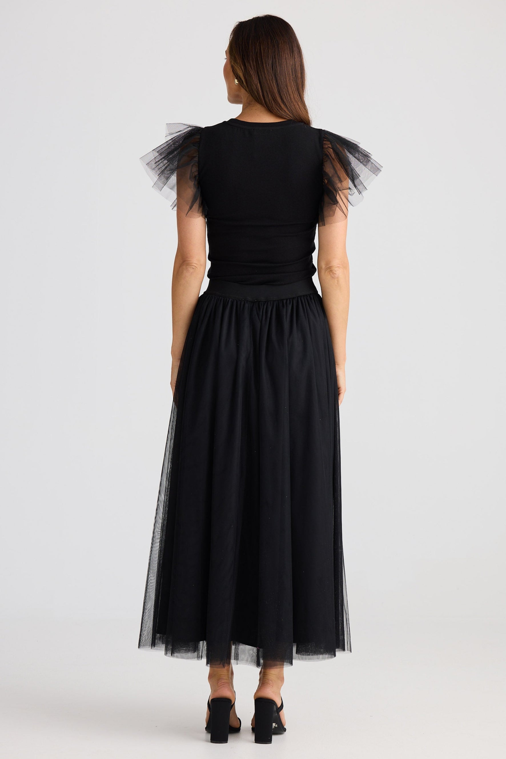 Woman wearing a black dress with tulle sleeves on a white background