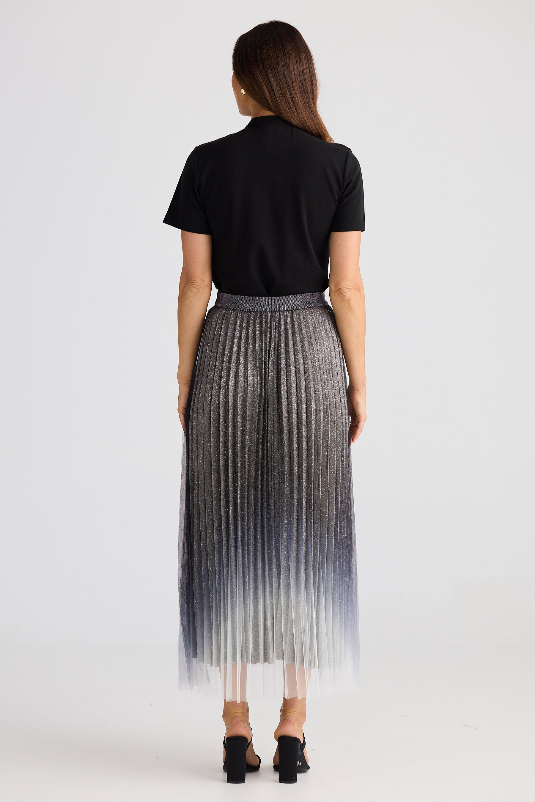 Woman wearing a black top and gray pleated skirt with gradient effect on a white background