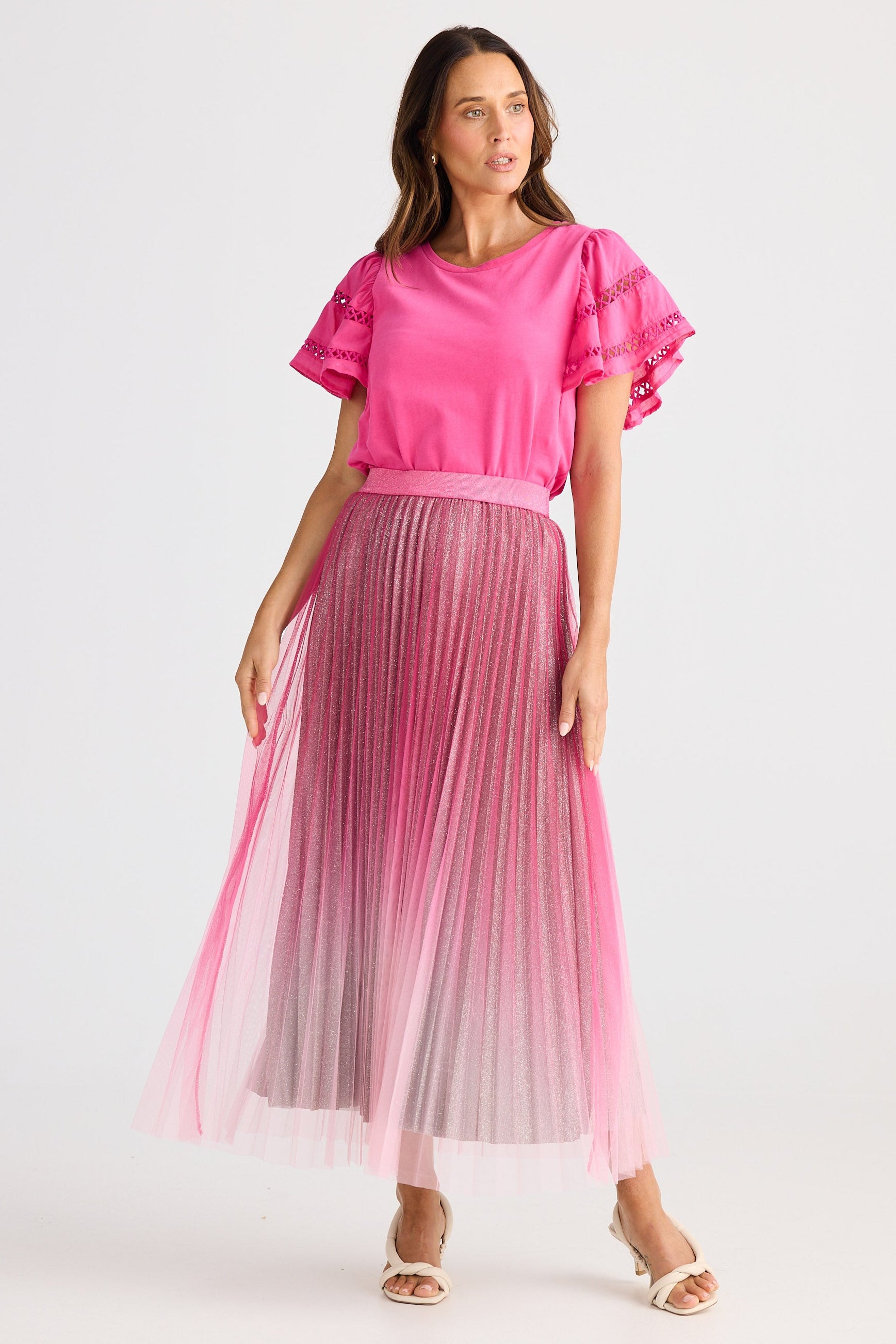 Woman wearing a pink blouse and pleated skirt on a white background