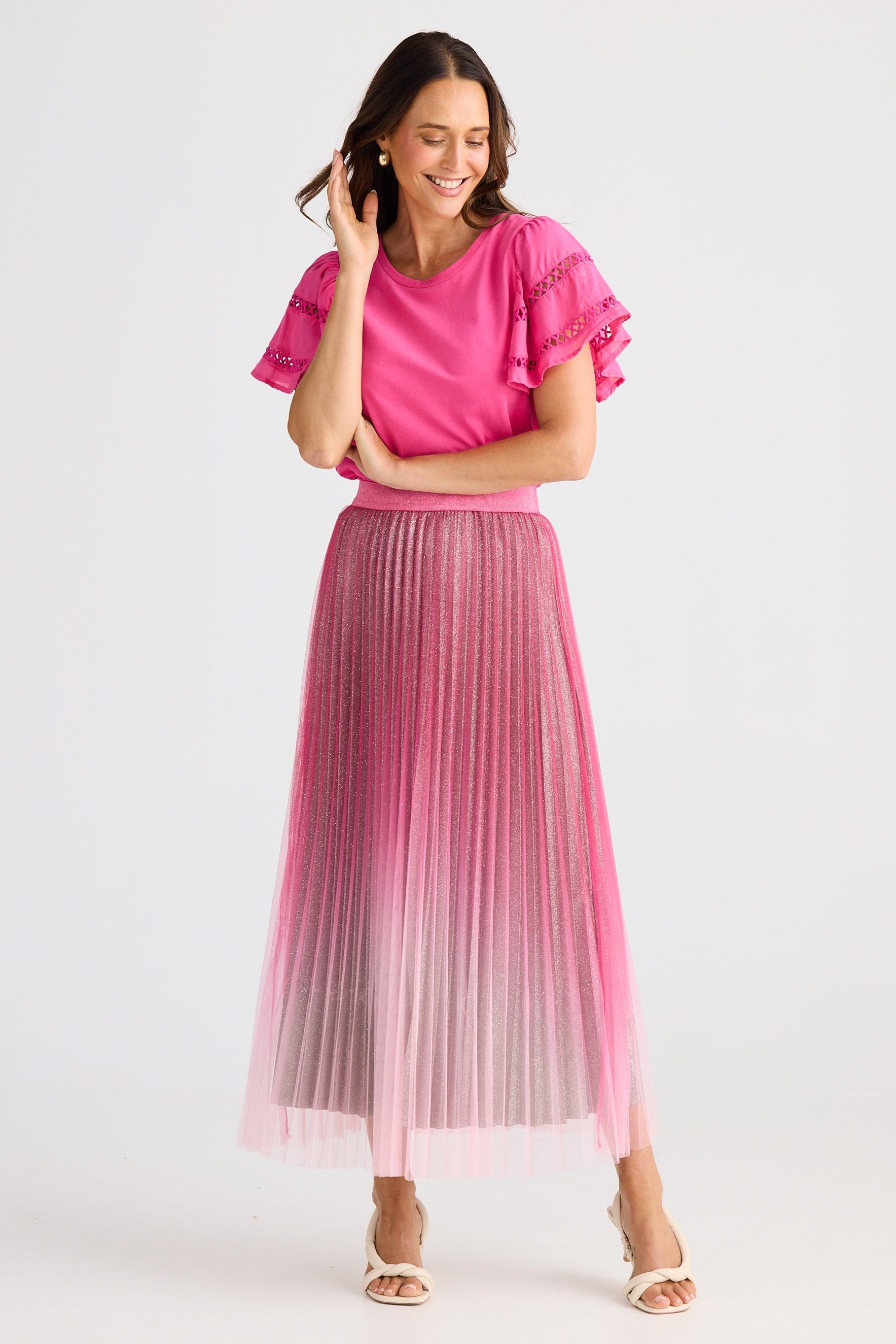 Woman wearing a pink outfit with a pleated skirt on a white background