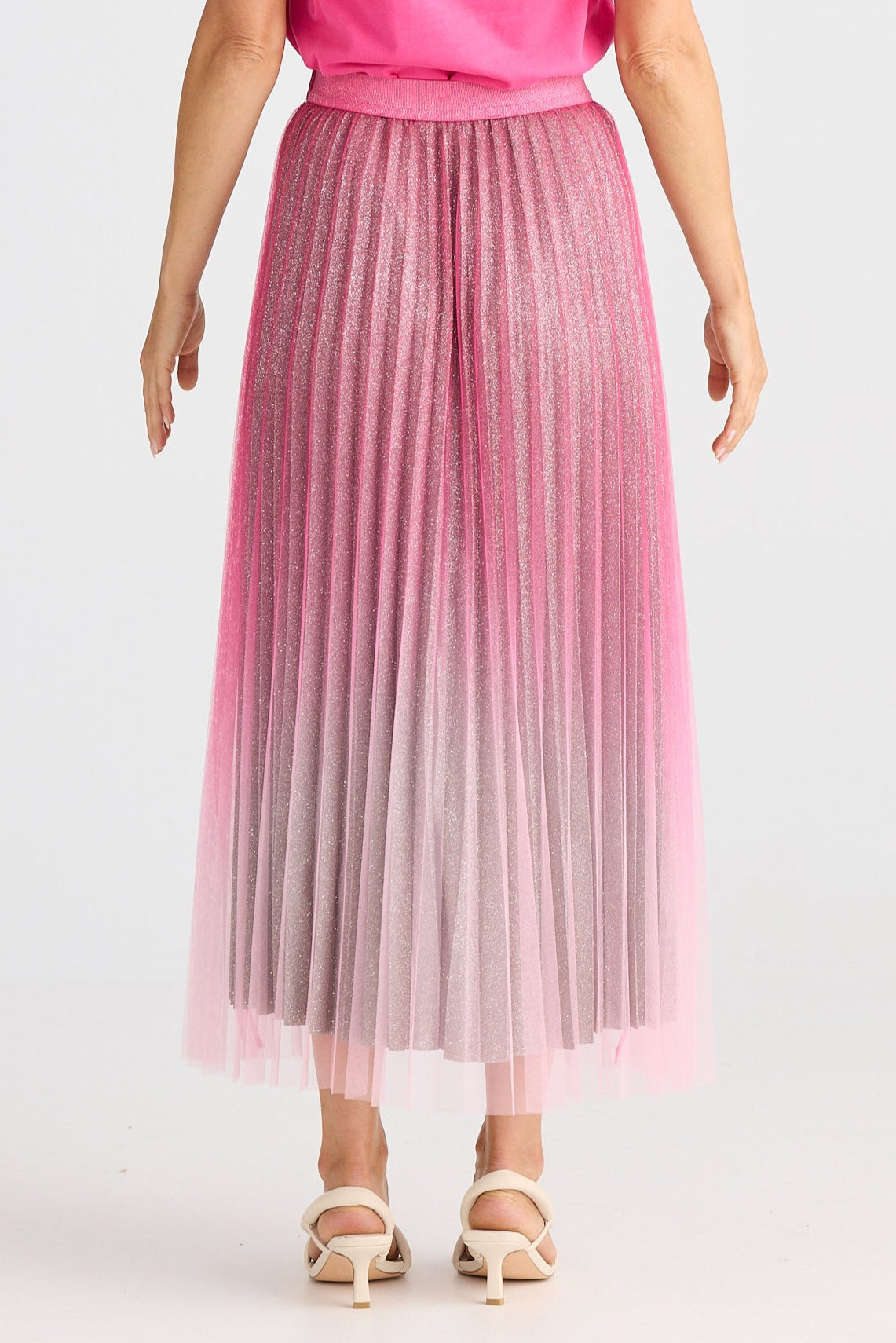 Woman wearing a pink outfit with a gradient skirt on a white background